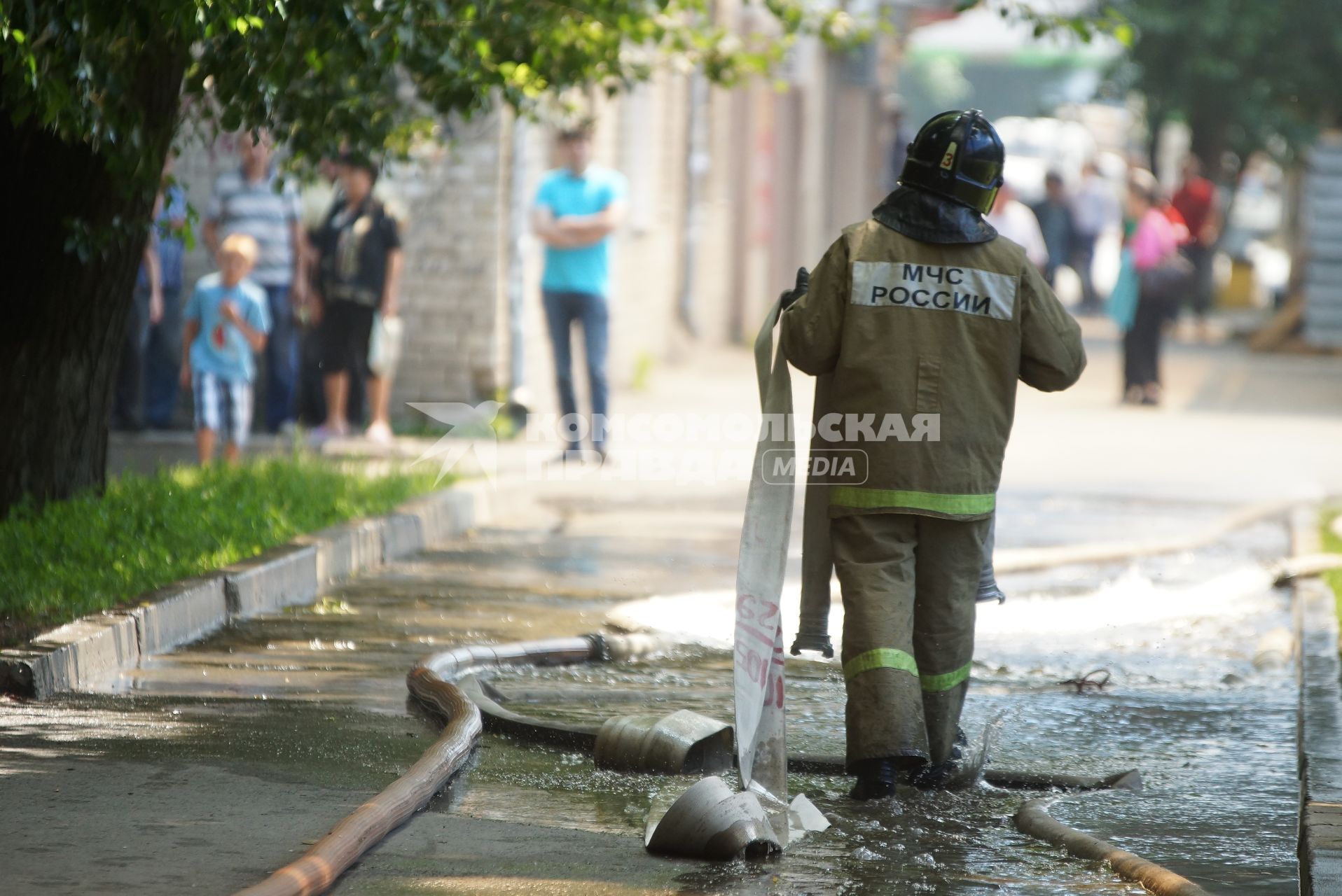 Пожарный идет по тротуару залитому водой от тушения пожара дом в Екатеринбурге