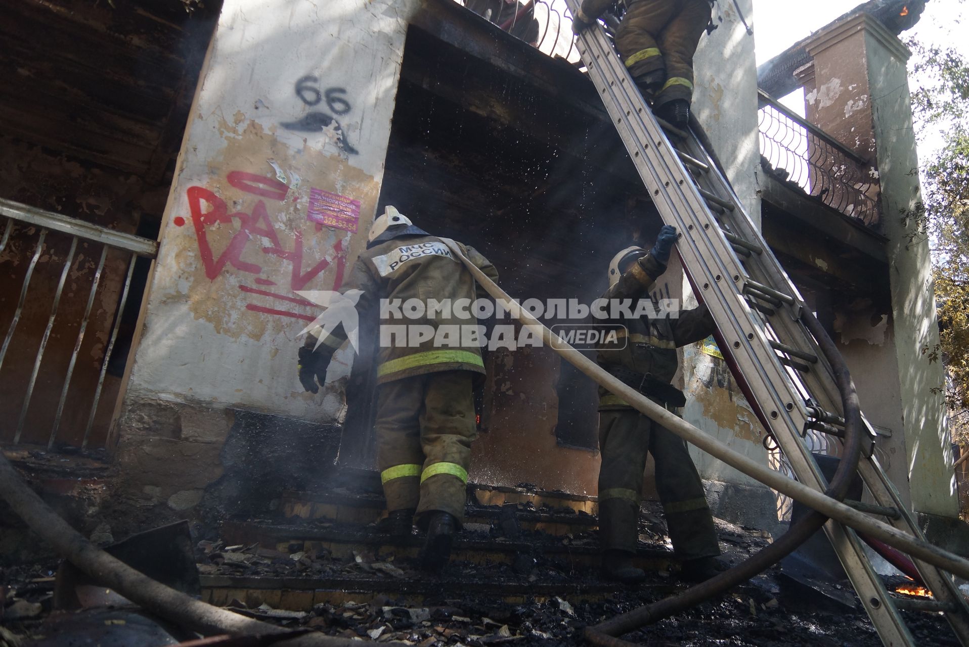 Пожарный с рукавом заходит в горящий дом