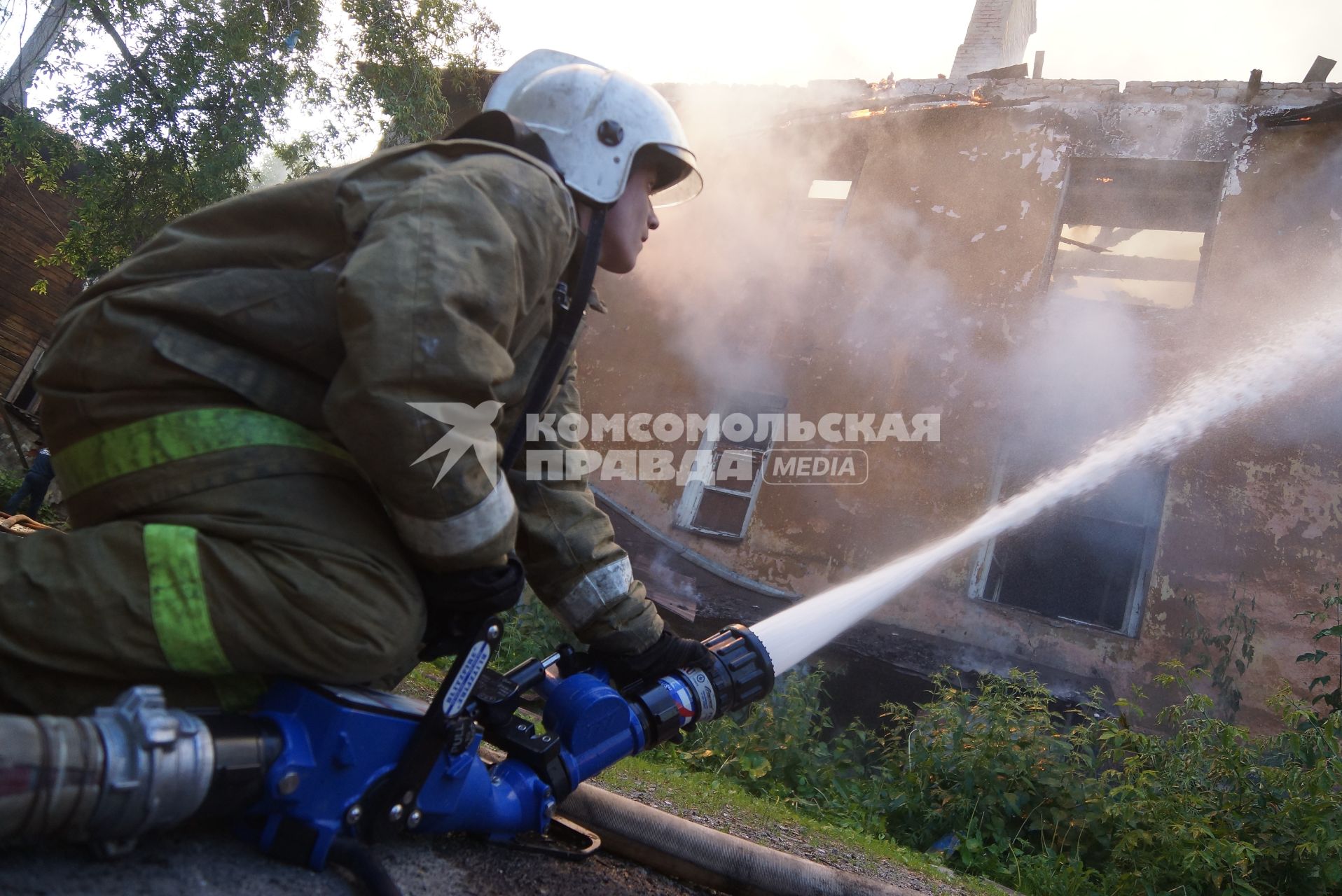 Пожарный тушит горящий дом в Екатеринбурге