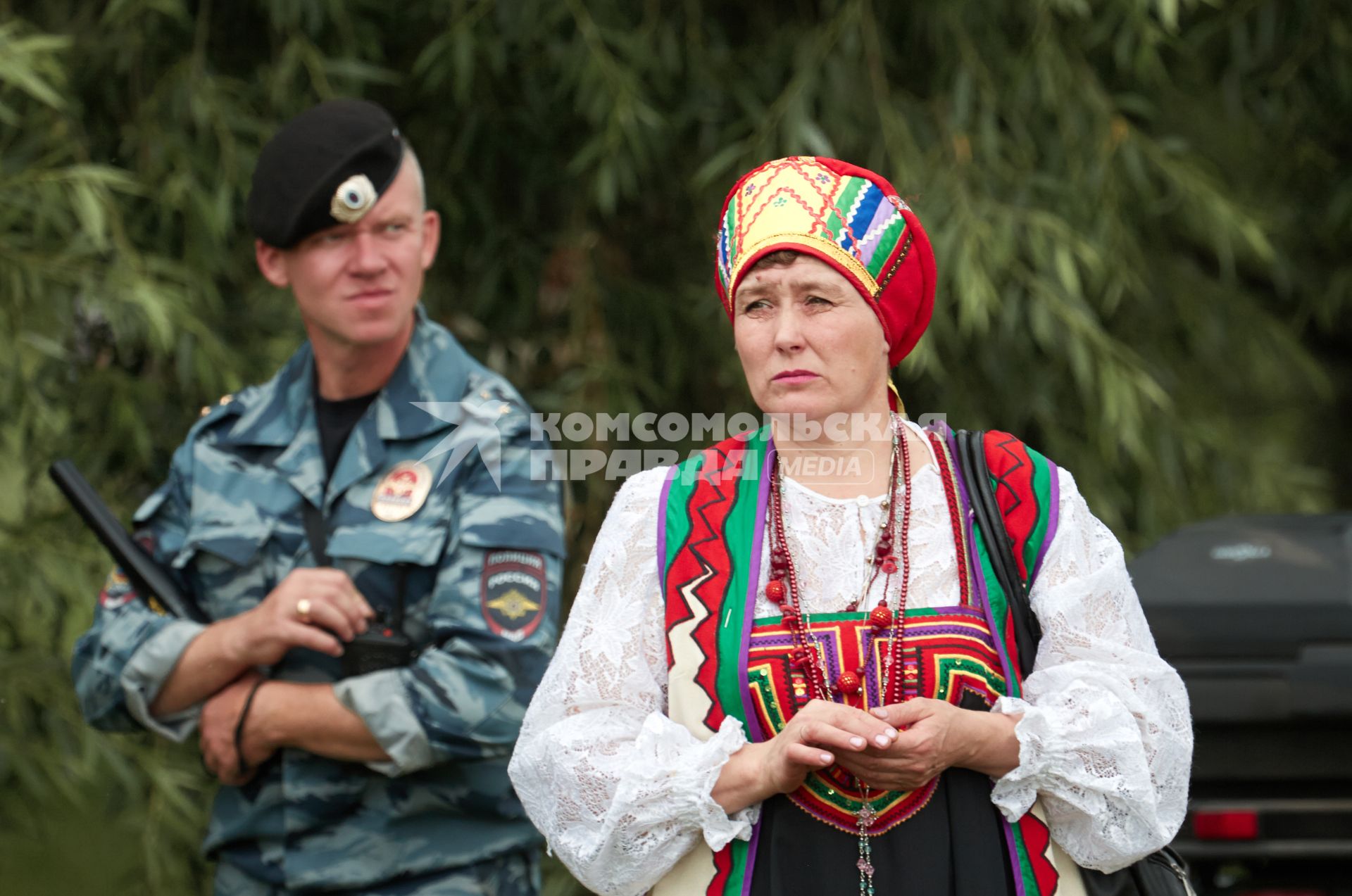 Женщина в национальном костюме на фоне полицейского с дубинкой.