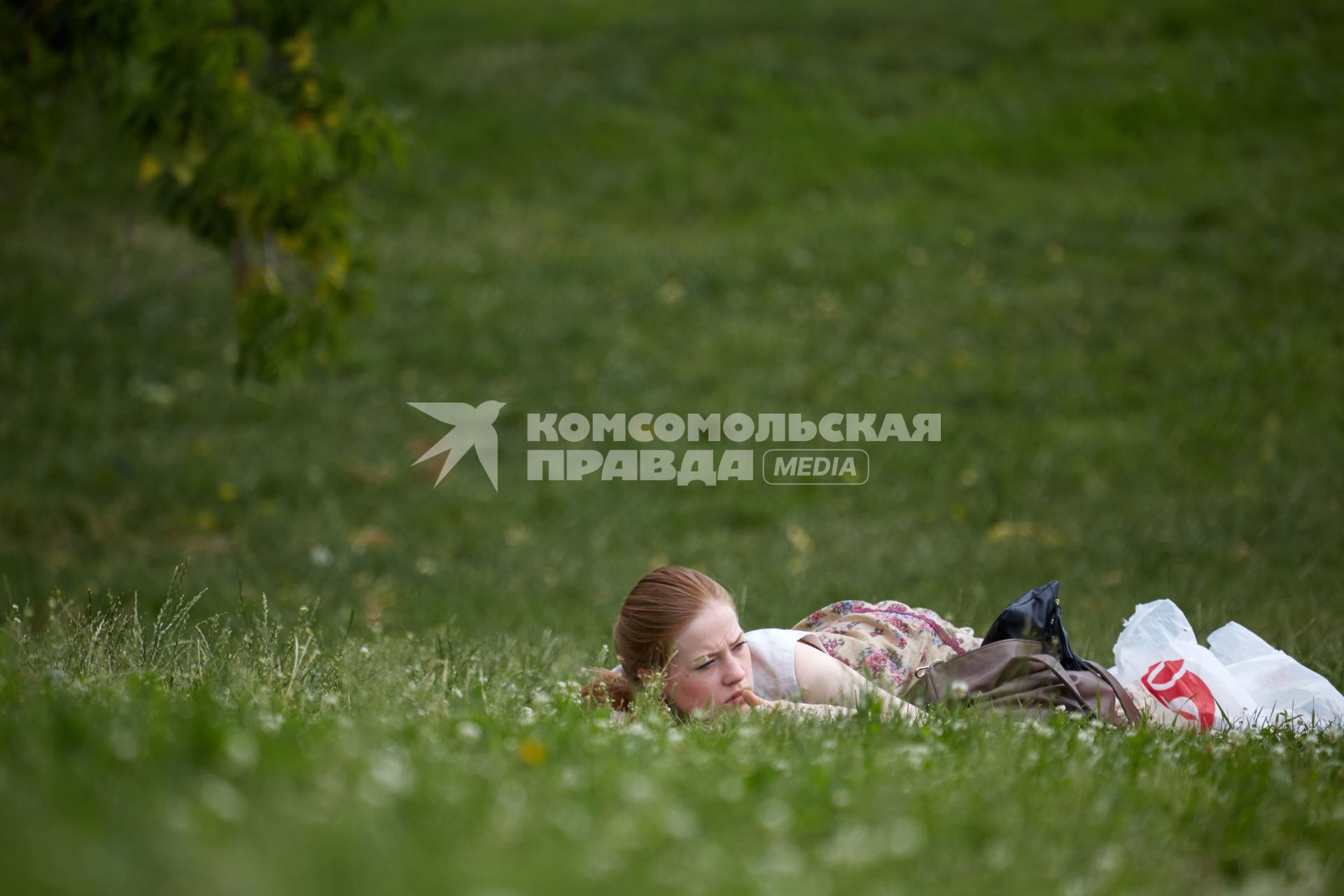 Девушка отдыхает на газоне в парке.