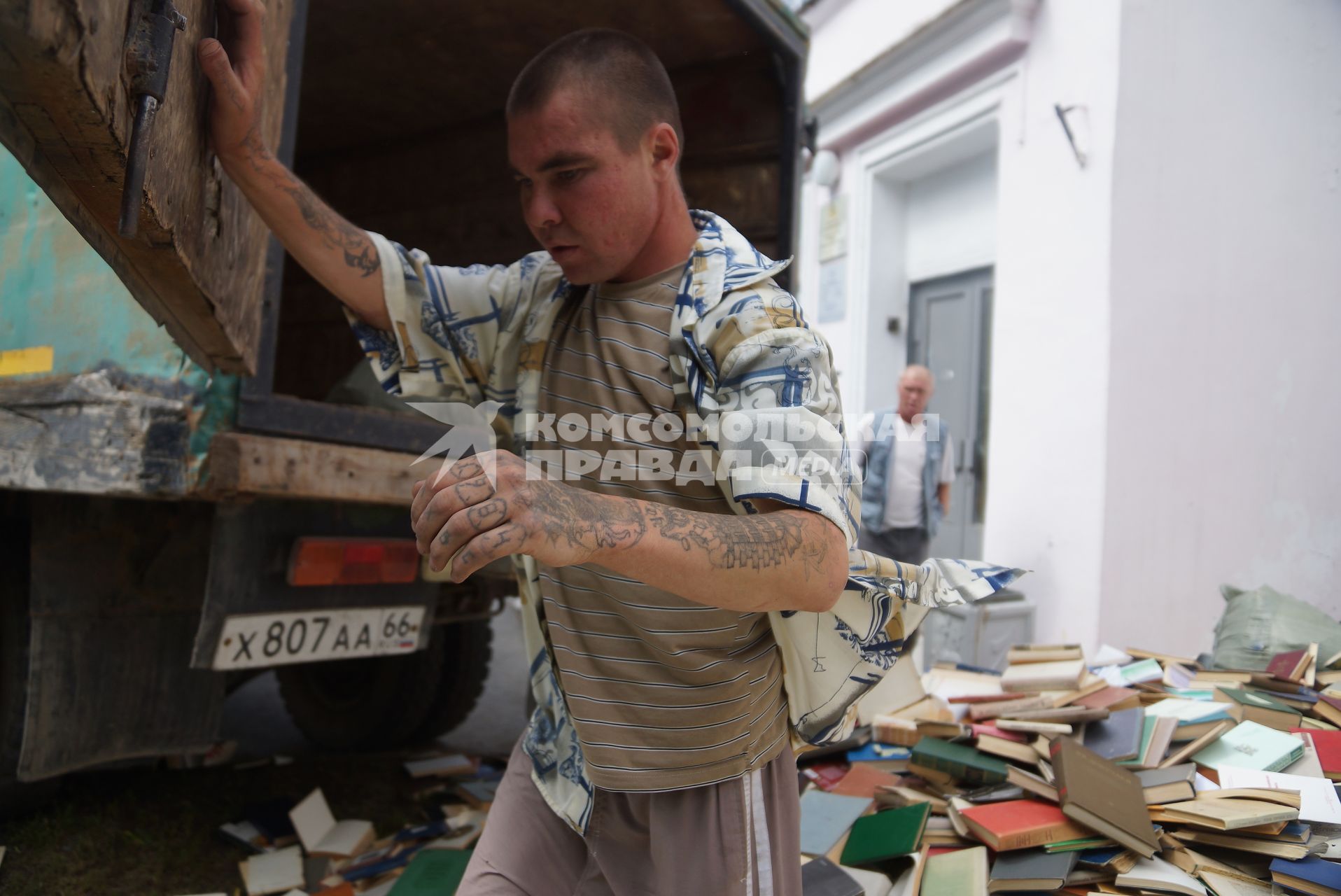 Библиотека дома Учителя в Екатеринбурге избавлялась от неликвидных книг выкидывая их в окно с 3-го этажа. парень с наколками на руках открывает дверцу фуры для погрузки книг