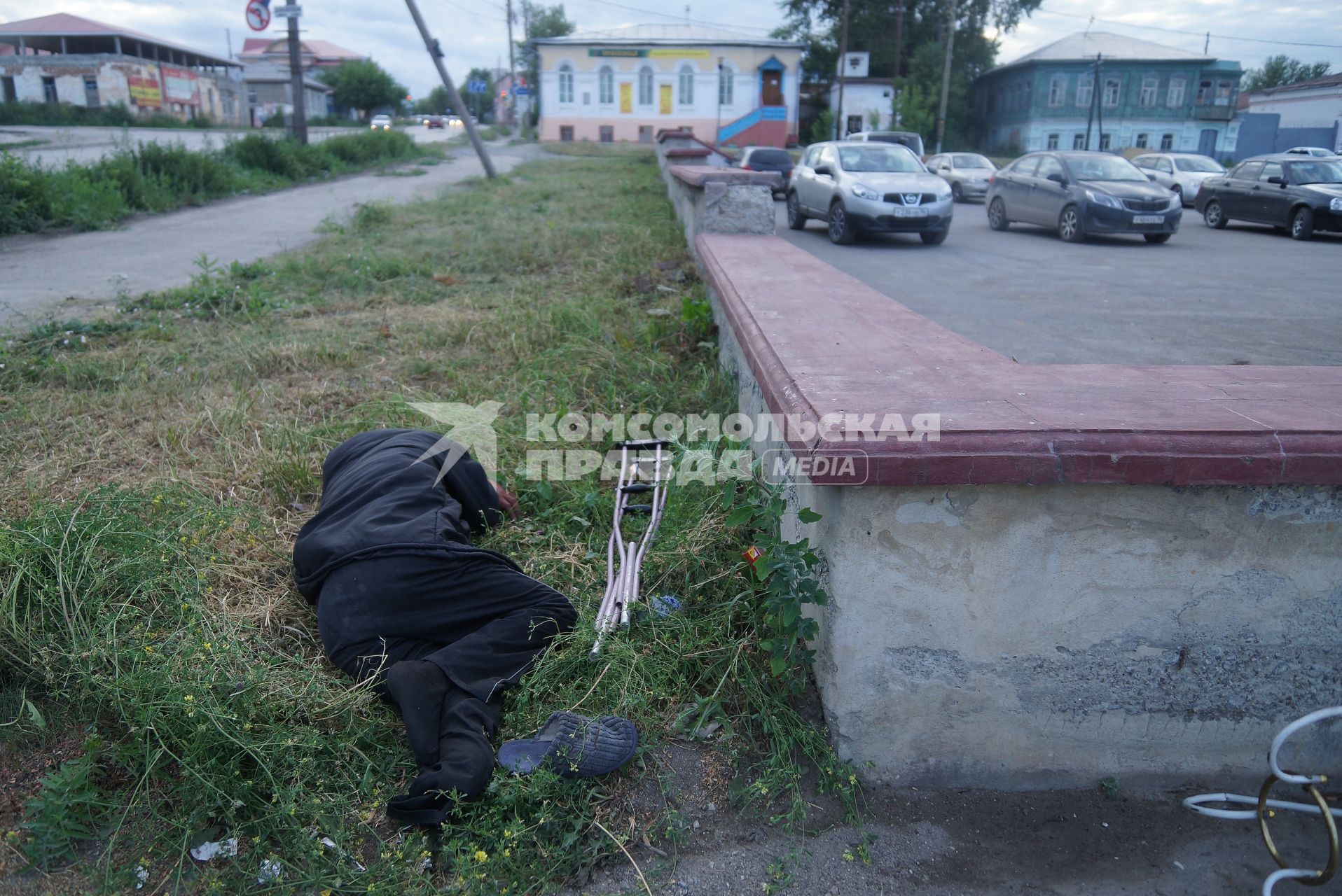 пьяный инвалид с костылями спит в траве в городе