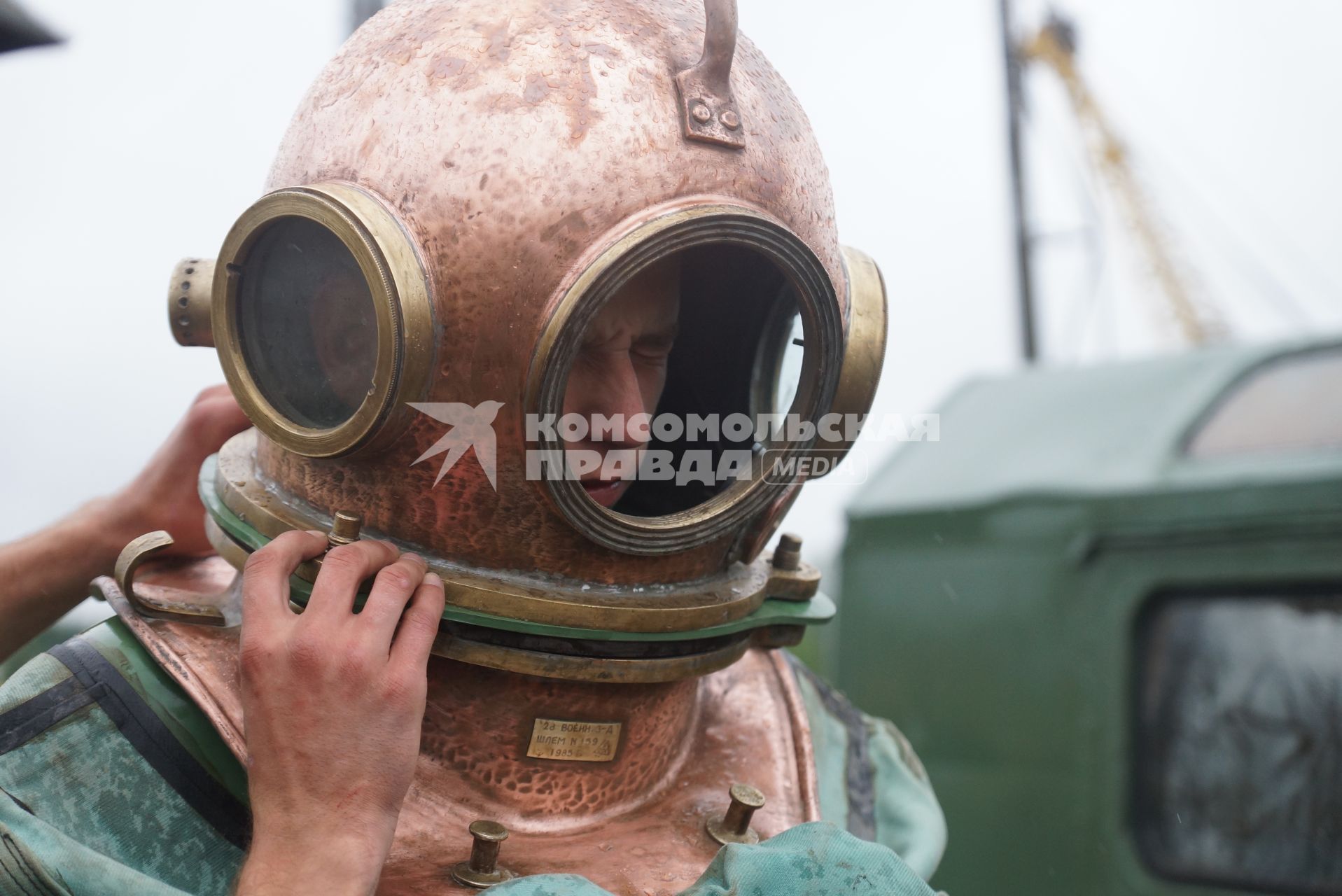 Солдат железнодорожных войск в водолазном костюме и тяжелом водолазном шлеме перед погружением