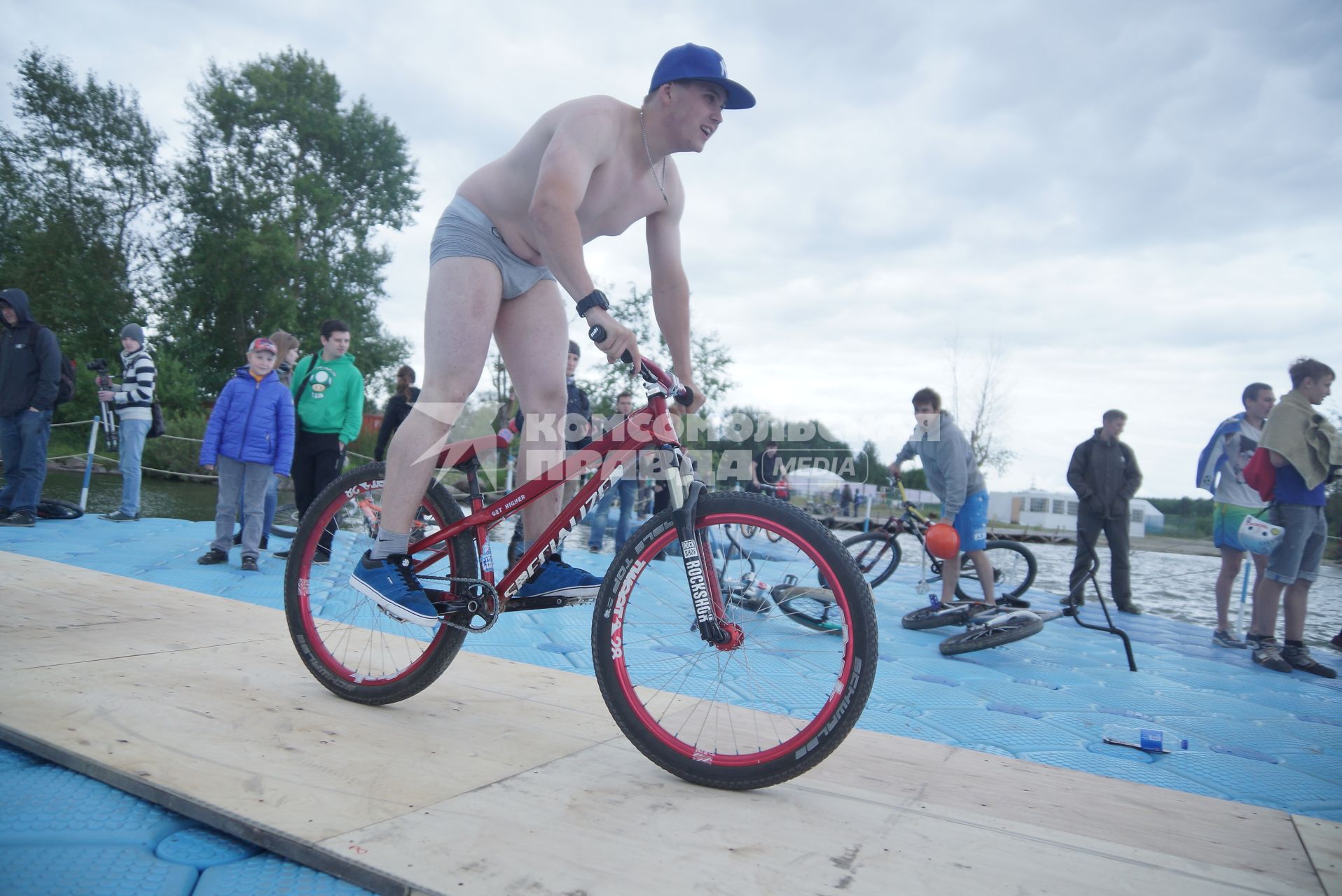 Прыжки на велосипедах в воду Bicycle live fest, парень в трусах едет к трамплину