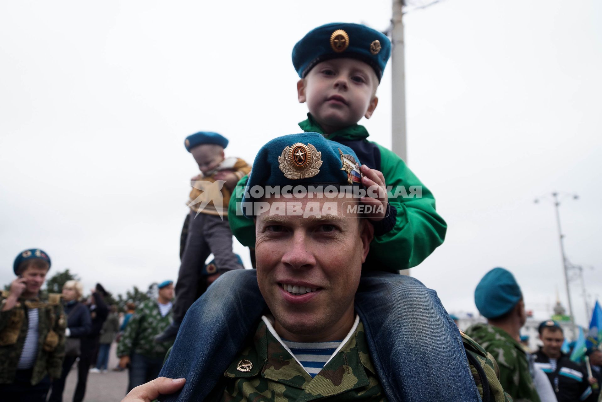 ветеран ВДВ с голубом берете и тельняжке с сыном на плечах