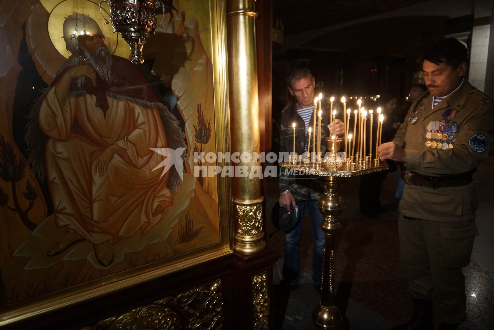 Ветераны ВДВ ставят свечи во время молебна в храме на крови