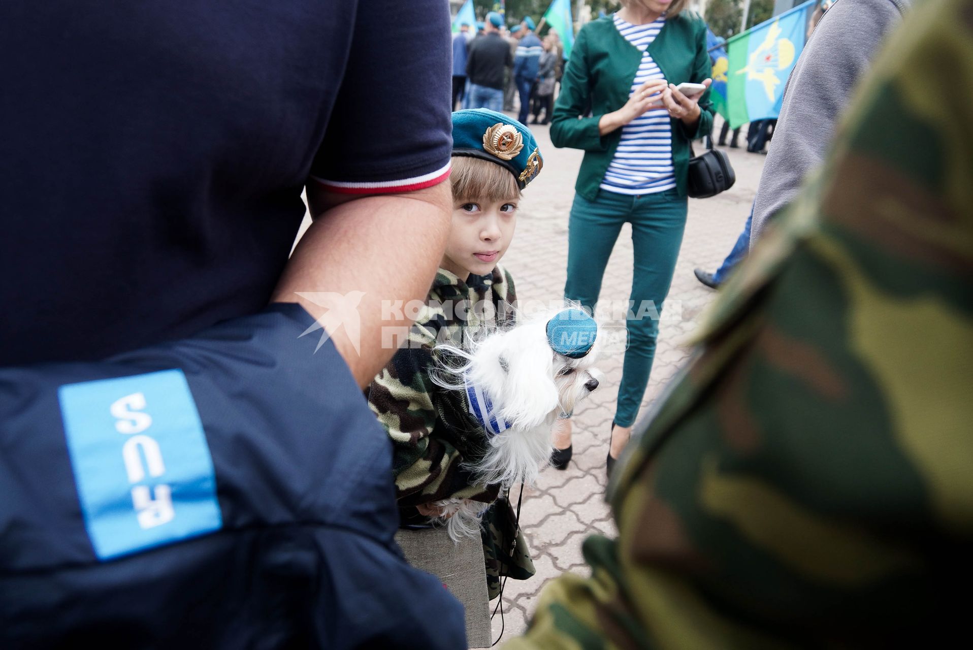 девочка держит на руках мальтийскую болонку с голубом берете во время празднования дня ВДВ в Екатеринбурге