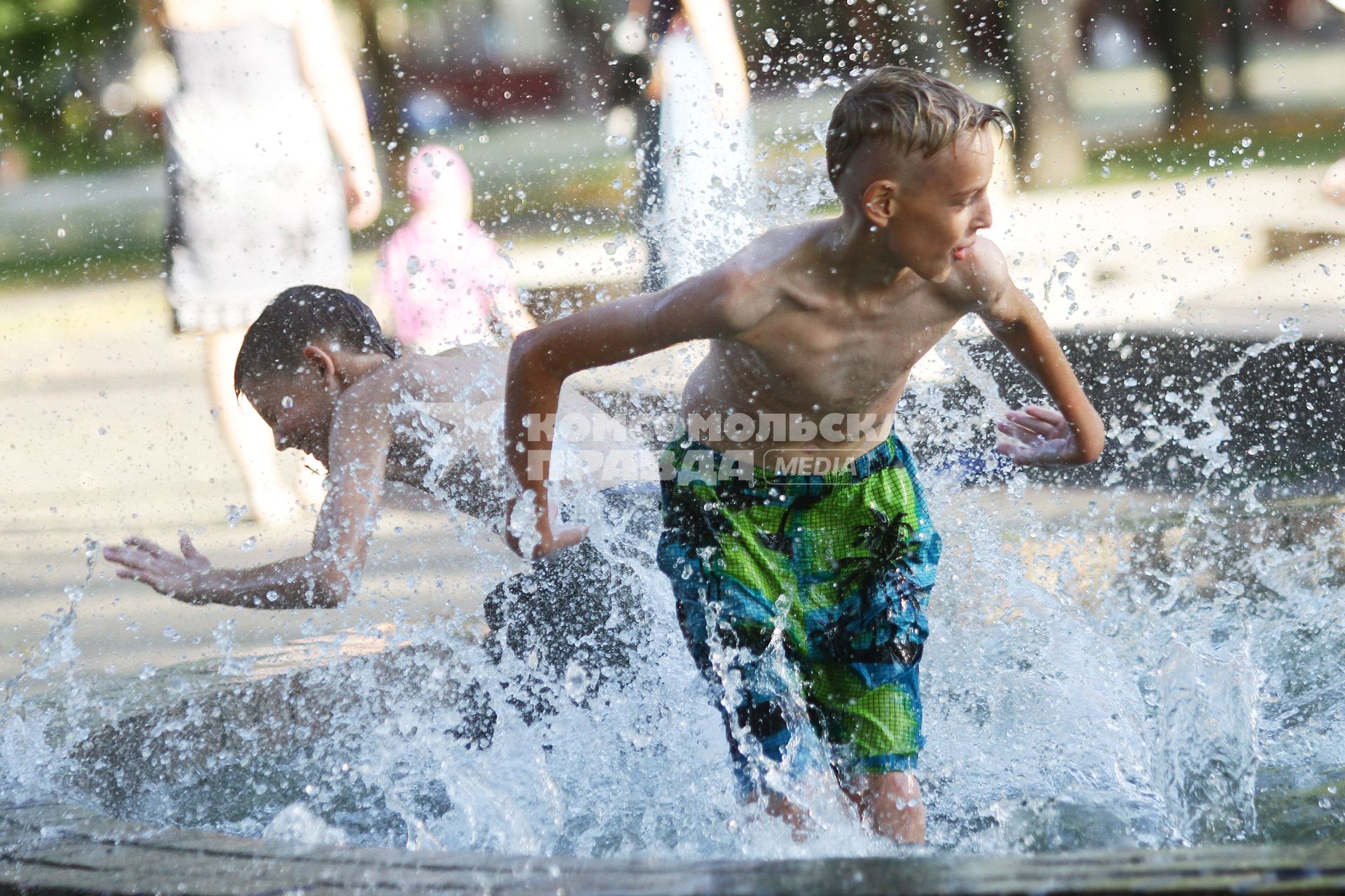 Дети играют в городском фонтане