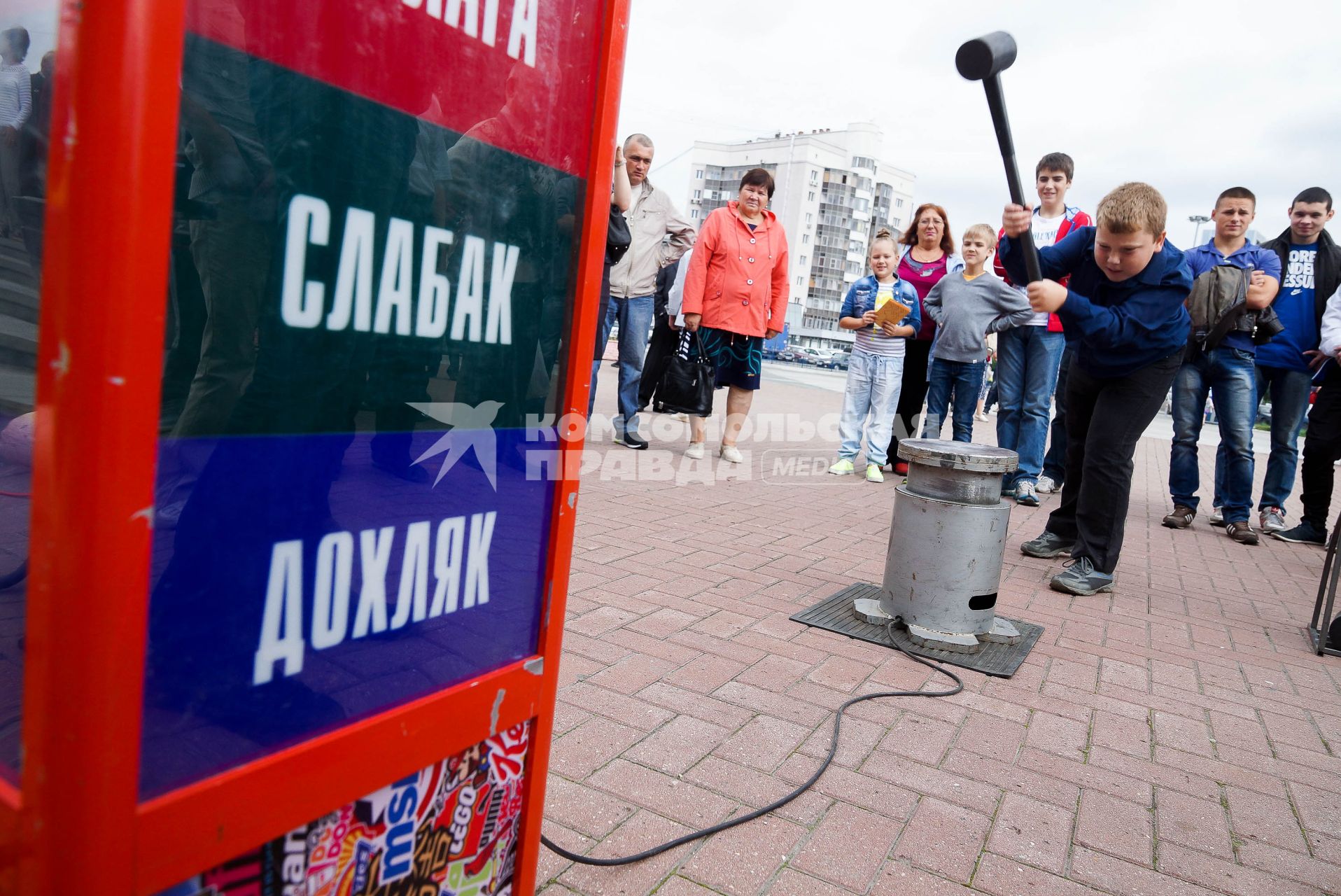 Мальчик в день физкультурника бьет кувалдой по наковальне силомера