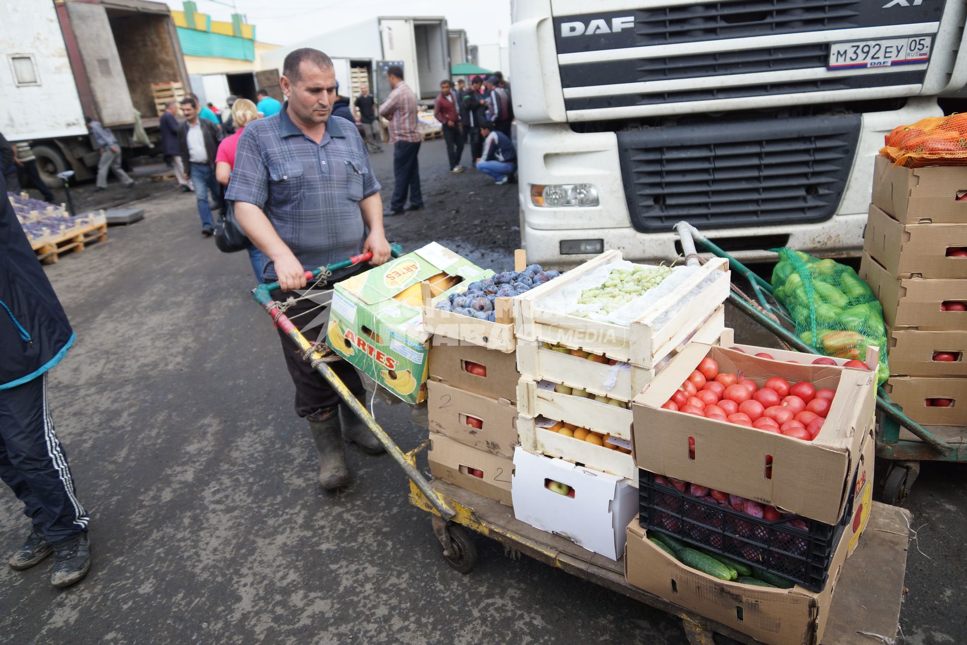 рабочий 4-й овощебазы в Екатеринбурге везет тележку с овощами и фруктами