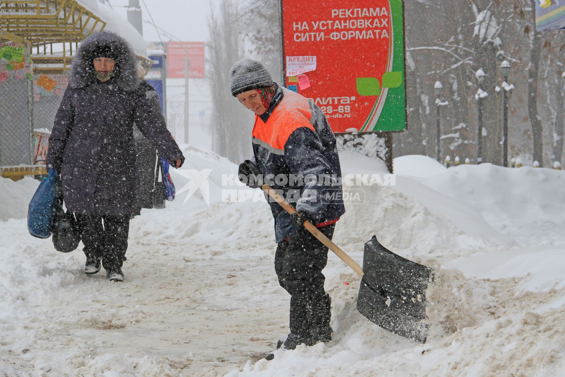 Снегопад. Женщина дворник чистит улицу от снега.