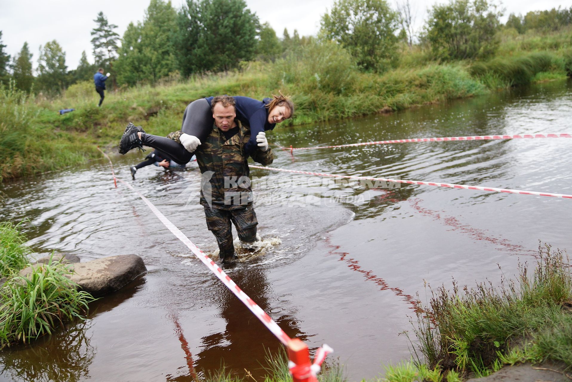 Участник грязных гонок Ural Dirty Race 2014 под Екатеринбургом  переходит речку в брод с напарницей на плечах