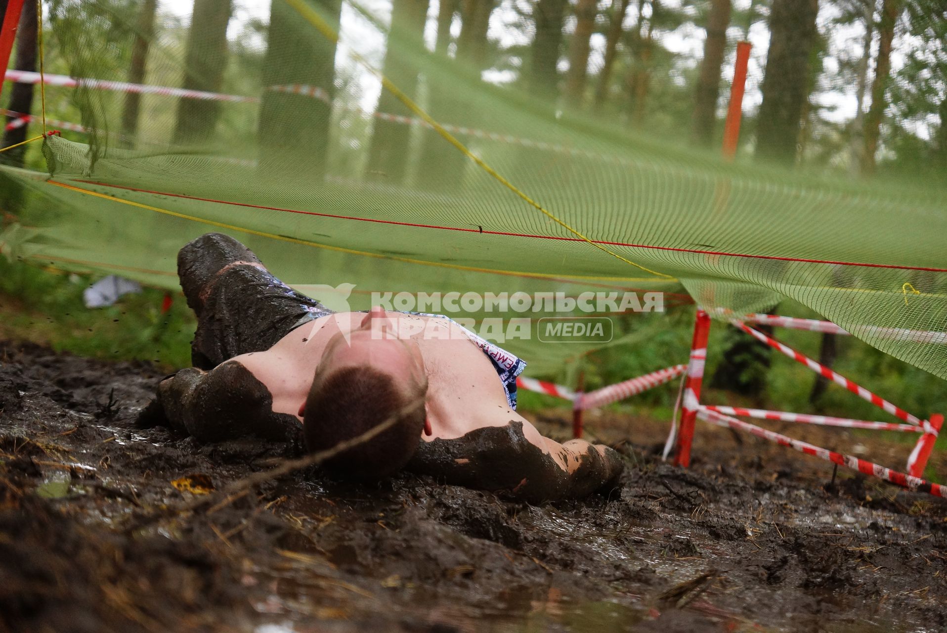 Участник грязных гонок Ural Dirty Race 2014 под Екатеринбургом  ползет на спине по грязи