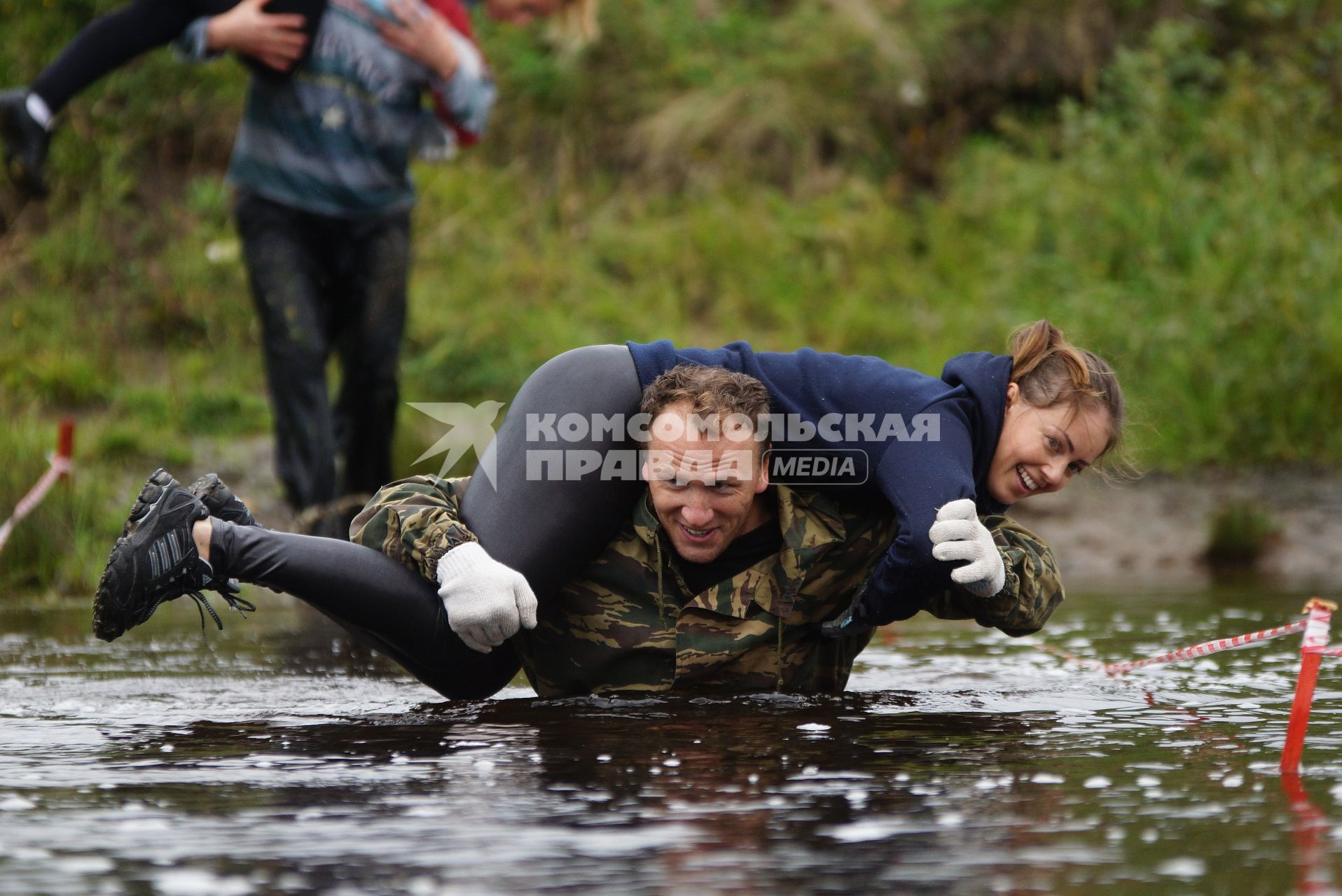 Участник грязных гонок Ural Dirty Race 2014 под Екатеринбургом  переходит речку в брод с напарницей на плечах