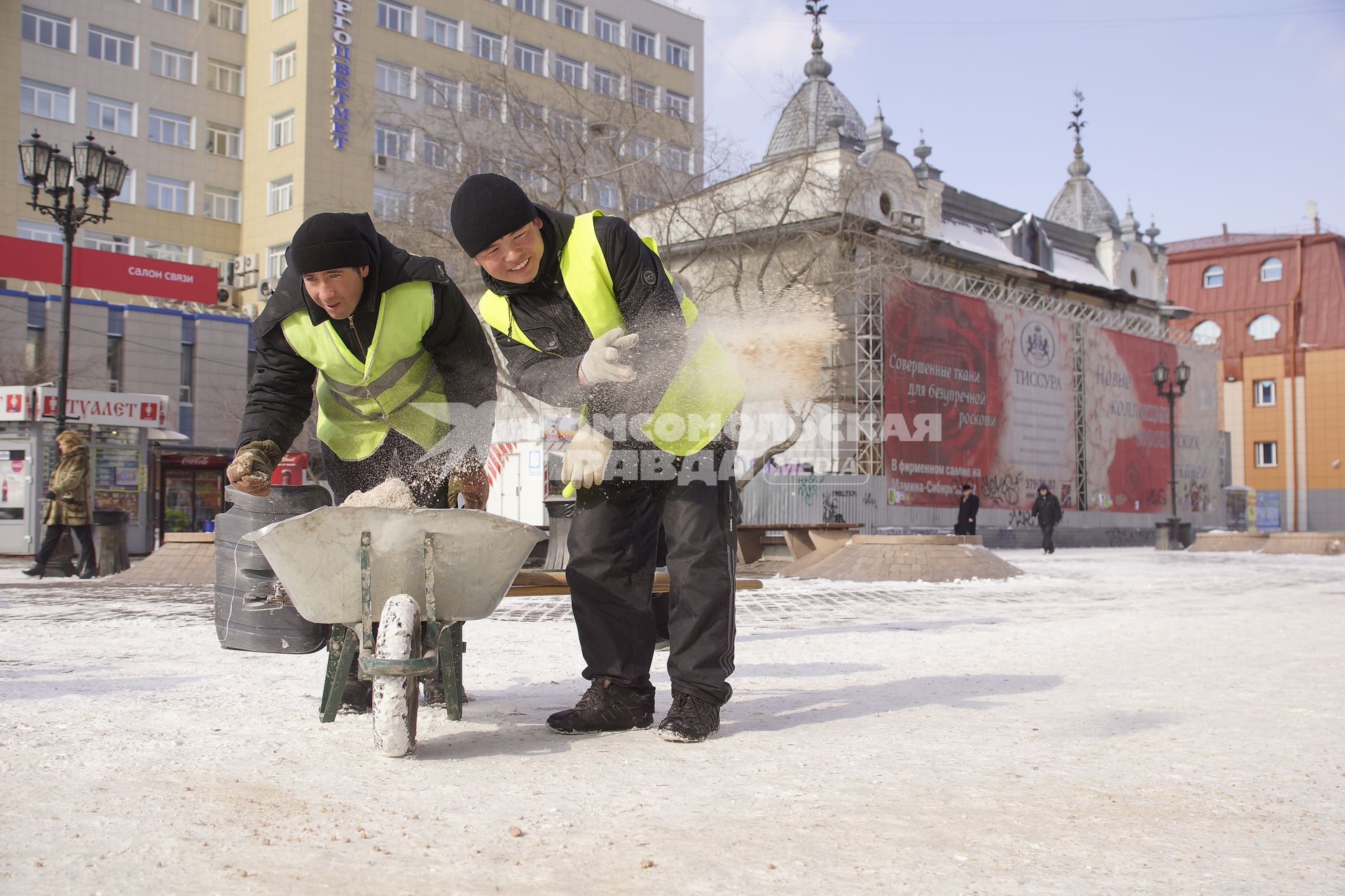 дворники разбрасывают антигололедную смесь по тротуару