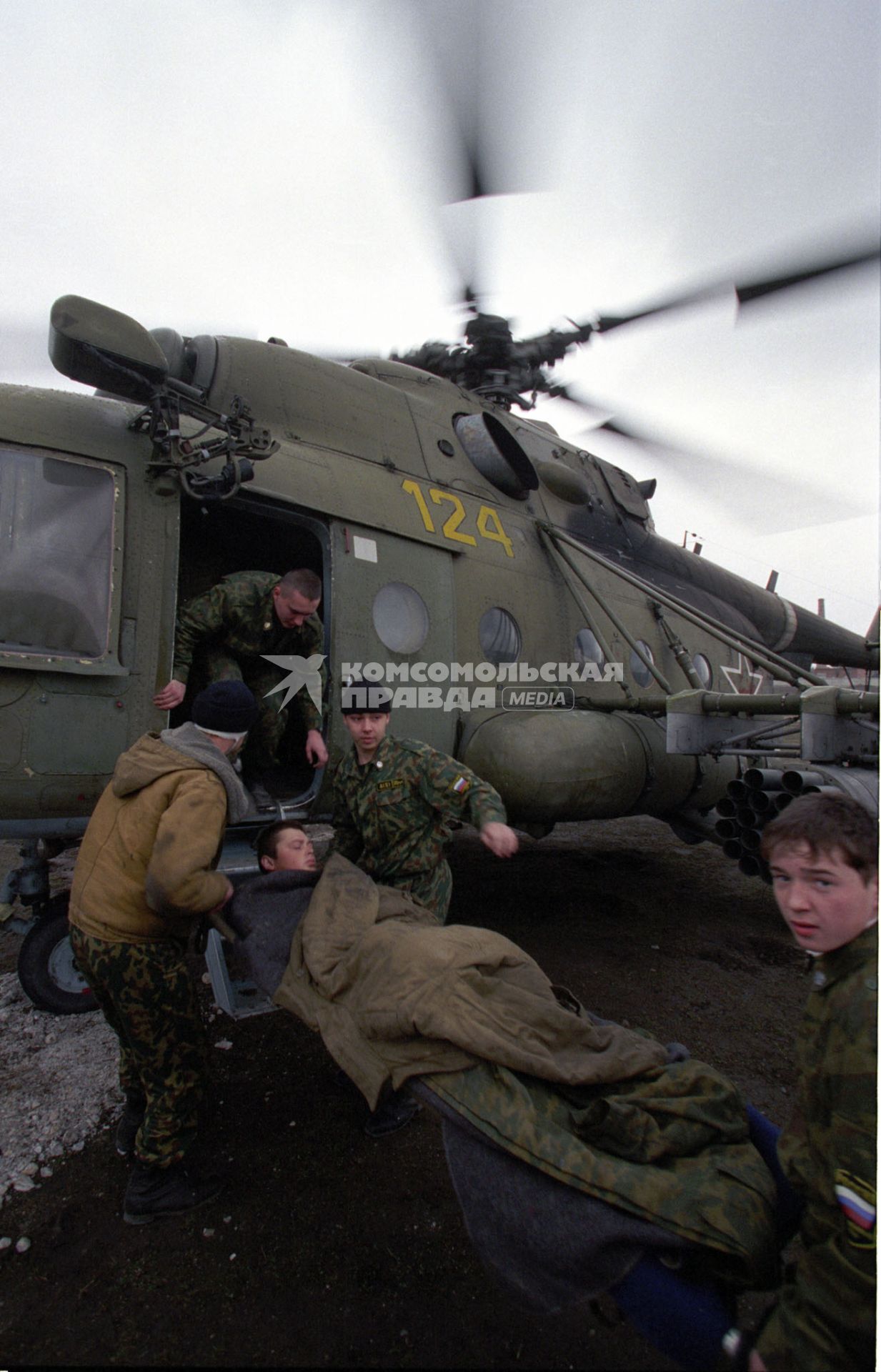 Вторая чеченская война. Урус-Мартан. Российские военнослужащие заносят на борт вертолета Ми-8 раненого бойца.