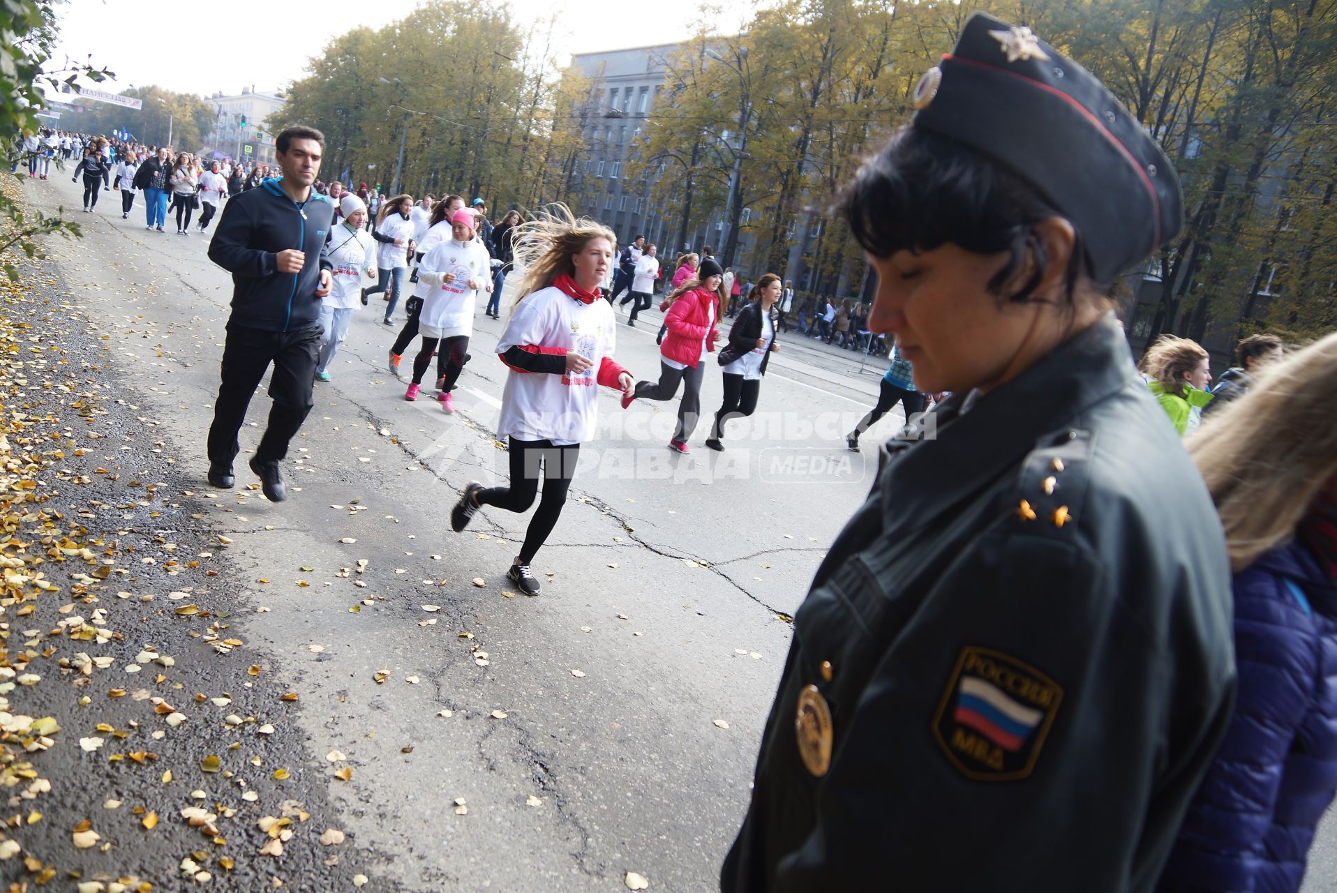 Участники забега \"Кросс нации 2014\" в Екатеринбурге пробегают мимо сотрудницы полиции в оцеплении