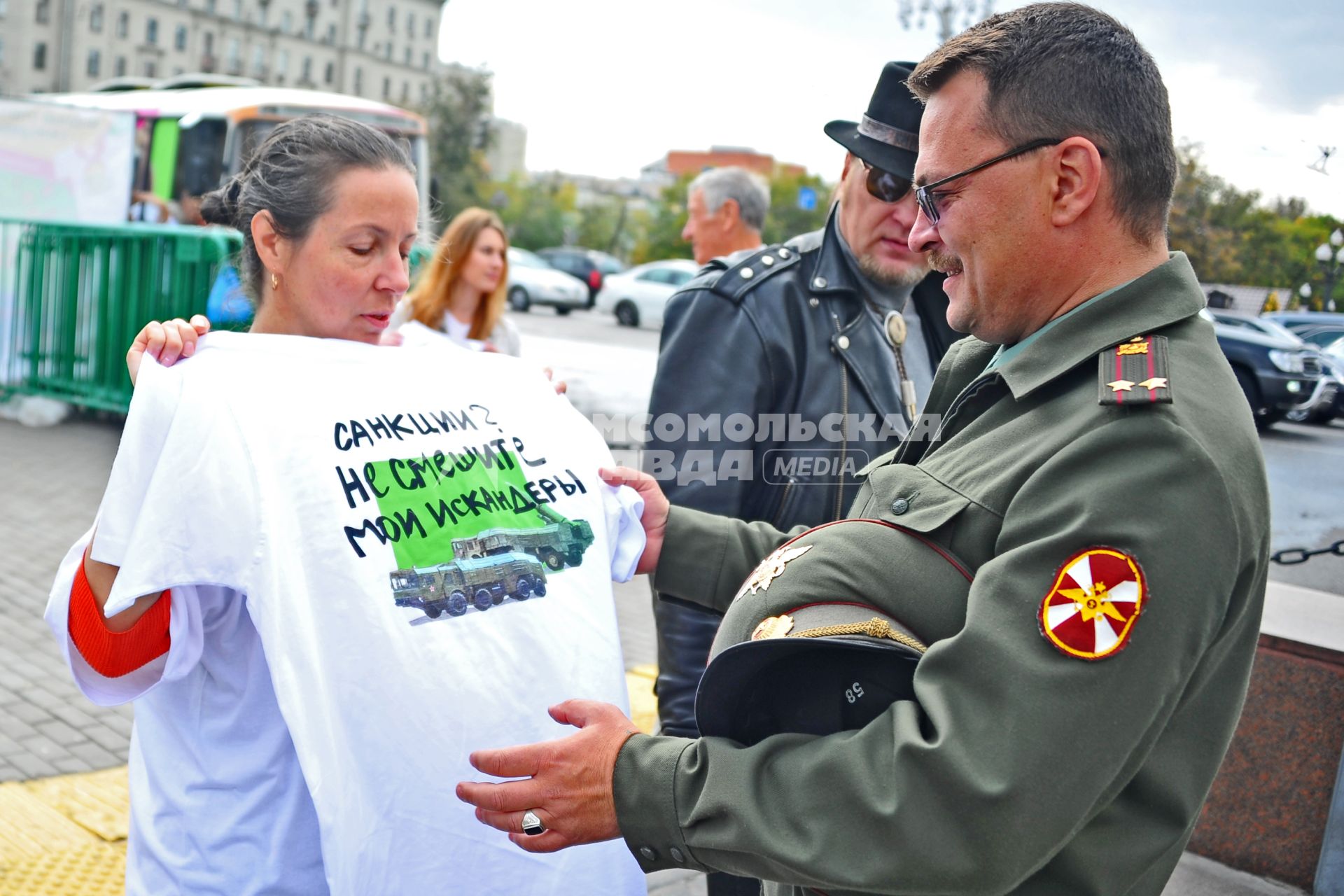 Акция \'Модный ответ - санкциям нет!\' на Пушкинской площади. На снимке: участница акции демонстрирует футболку `Санкции? Не смешите мои искандеры!` военнослужащему.