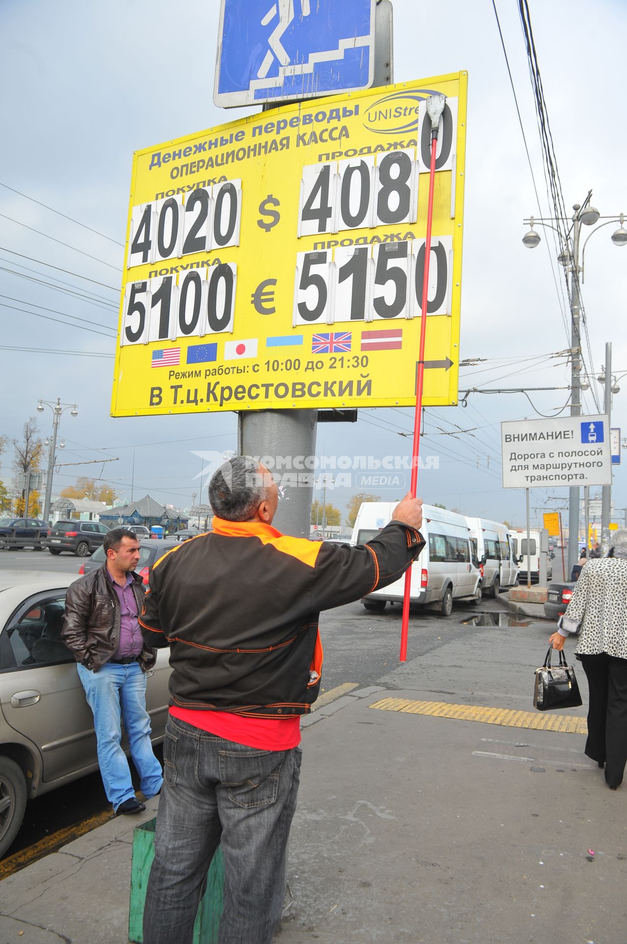 Мужчина меняет курс валюты на табло около метро `Рижская`.