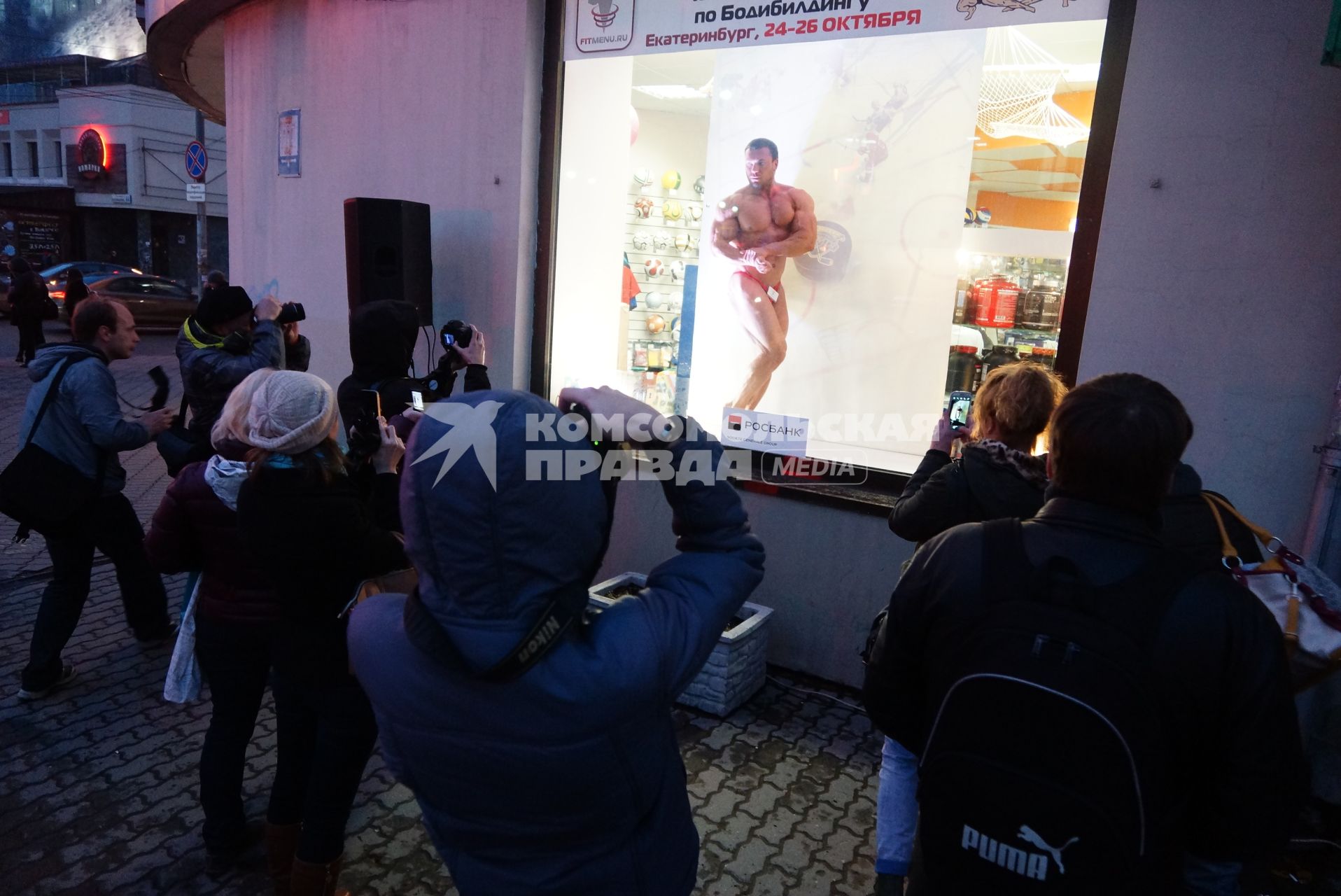 Прохожие фотографируют бодибилдера, во время акции \"Живые манекены\" в спортивном магазине Екатеринбурга