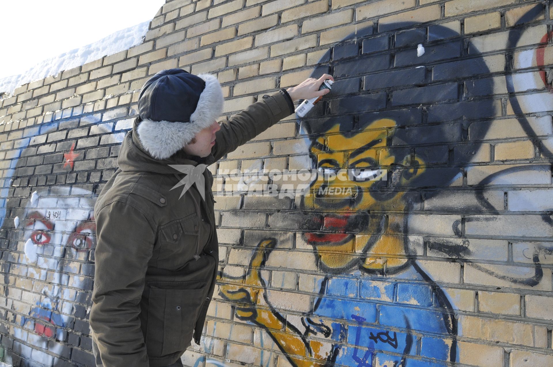 Мужчина рисует граффити на стене.