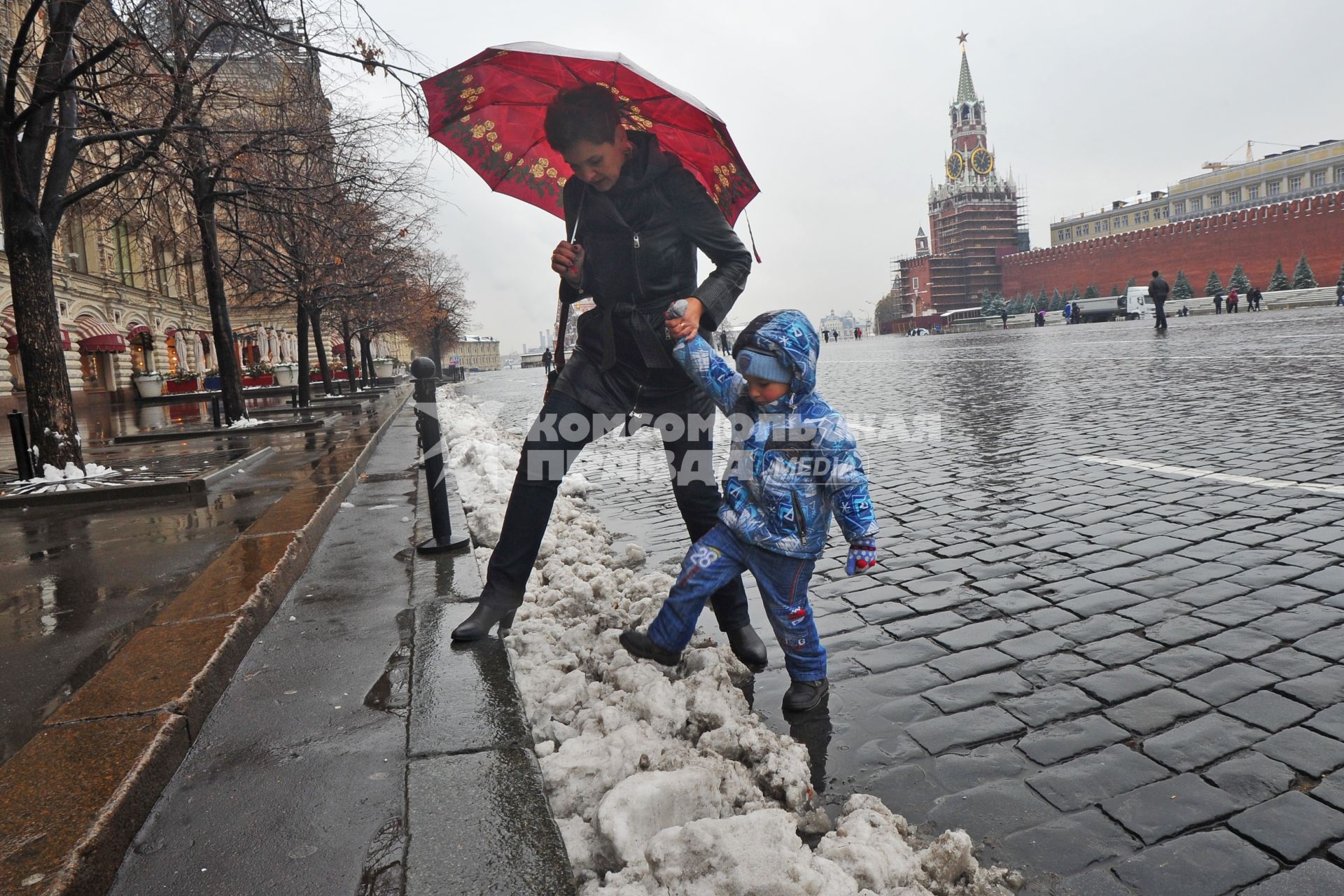 Первый снег в Москве. На снимке: женщина с ребенком перешагивают через снег на Красной Площади.