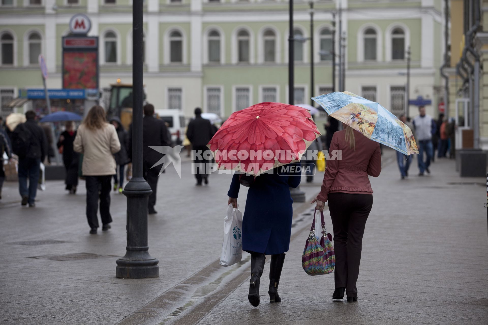 Люди гуляют под дождем.