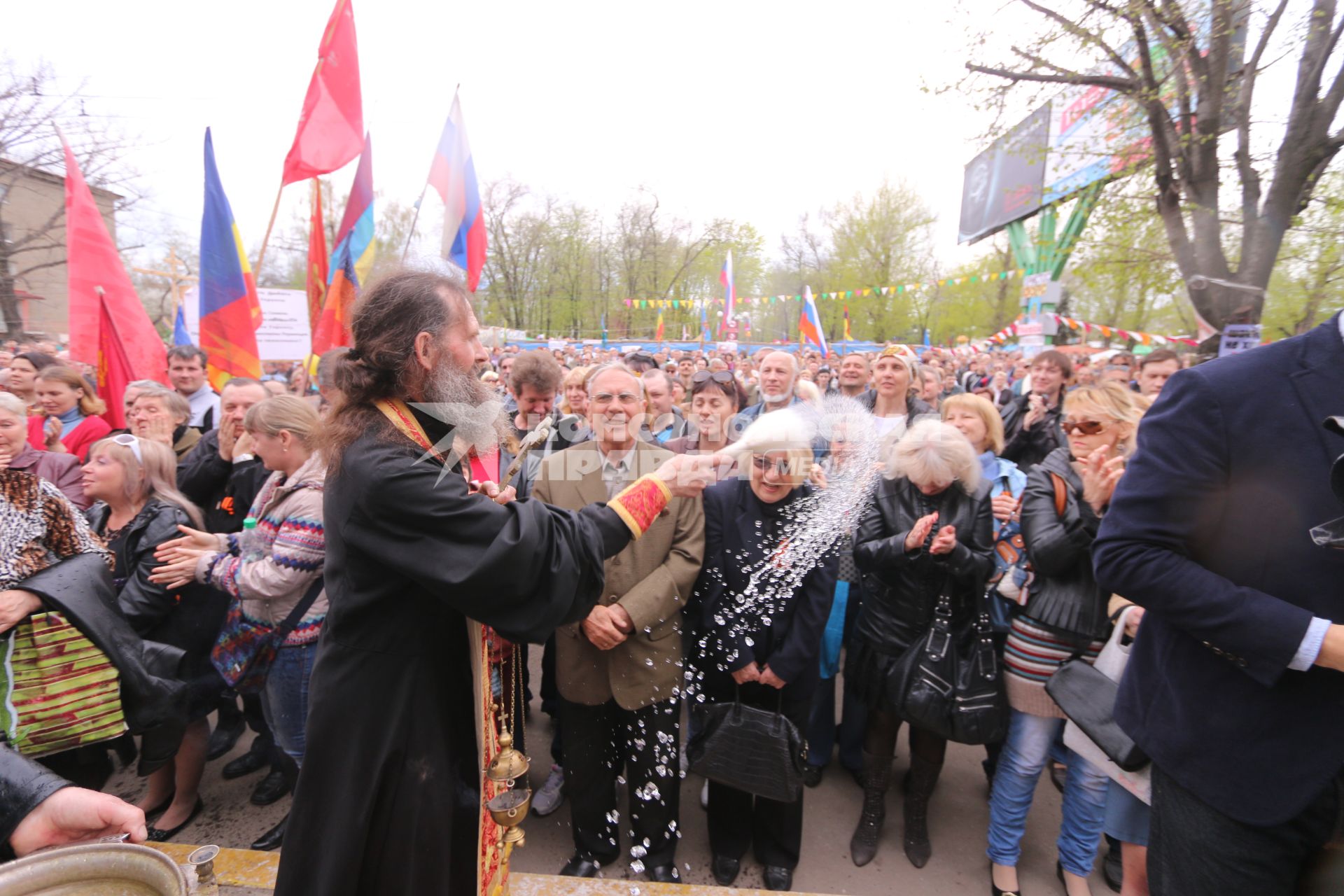 Ситуация в Луганске. На снимке: батюшка окропляет святой водой местных жителей во время Крестного хода. Люди направляются к зданию Службы безопасности Украины (СБУ) на митинг, где по завершению состоится народное голосование.