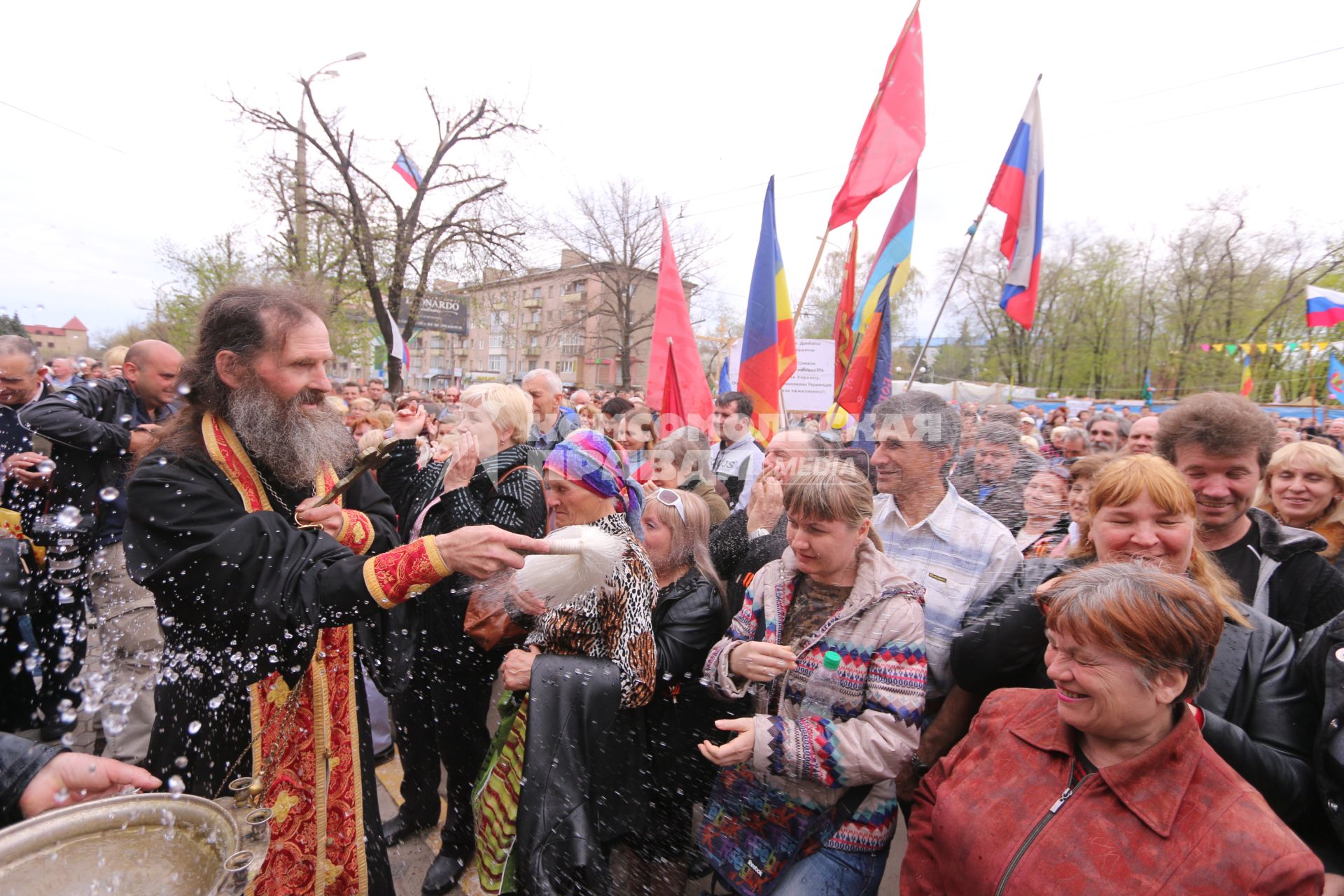 Ситуация в Луганске. На снимке: батюшка окропляет святой водой местных жителей во время Крестного хода. Люди направляются к зданию Службы безопасности Украины (СБУ) на митинг, где по завершению состоится народное голосование.