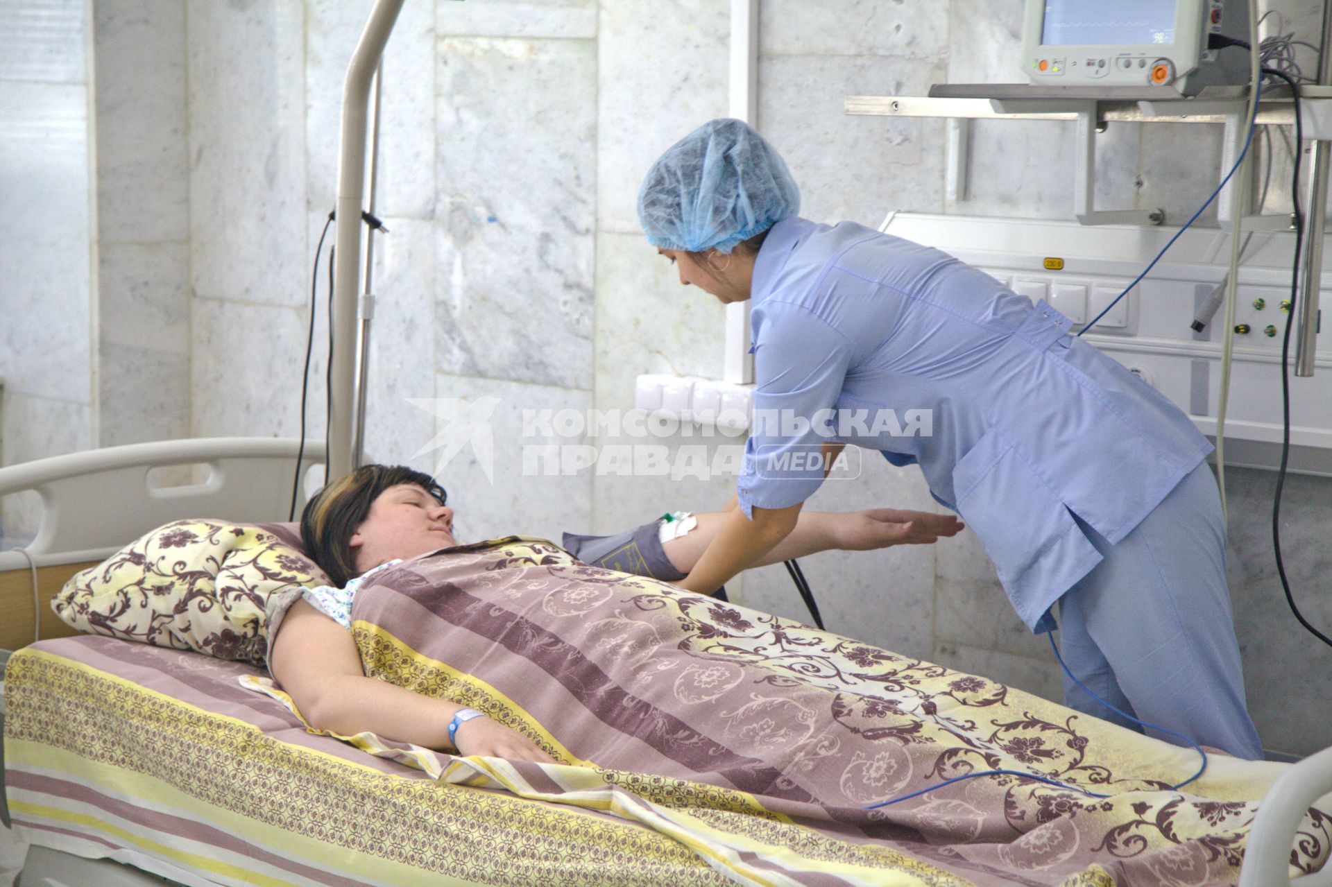 Медсестра подключает женщину к приборам в палате реанимации роддома БСМП №10