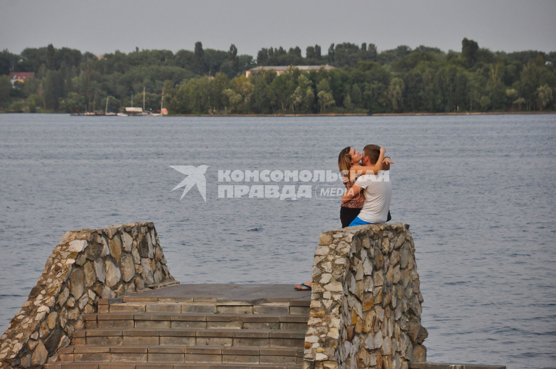 Влюбленная пара обнимается на набережной
