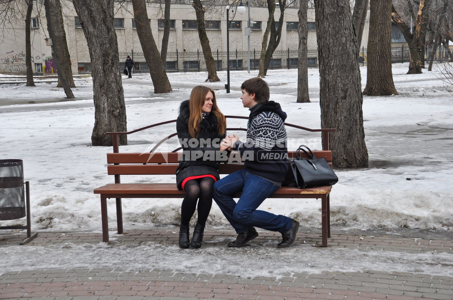 Парень и девушка сидят на лавочке, держась за руки.