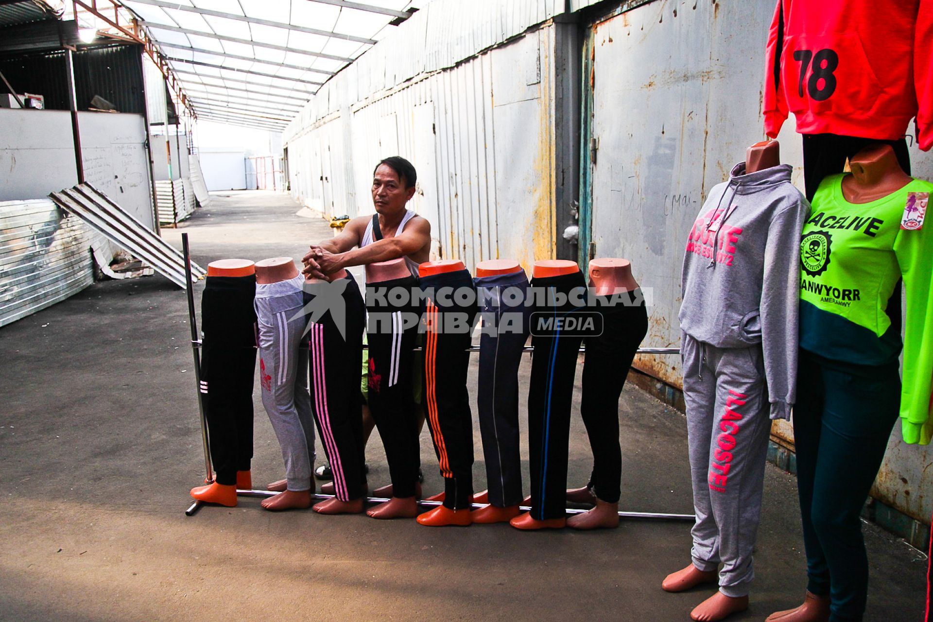 Вьетнамец стоит у манекенов со спортивной одеждой на рынке во время рейда УФМС по поиску нелегальных мигрантов
