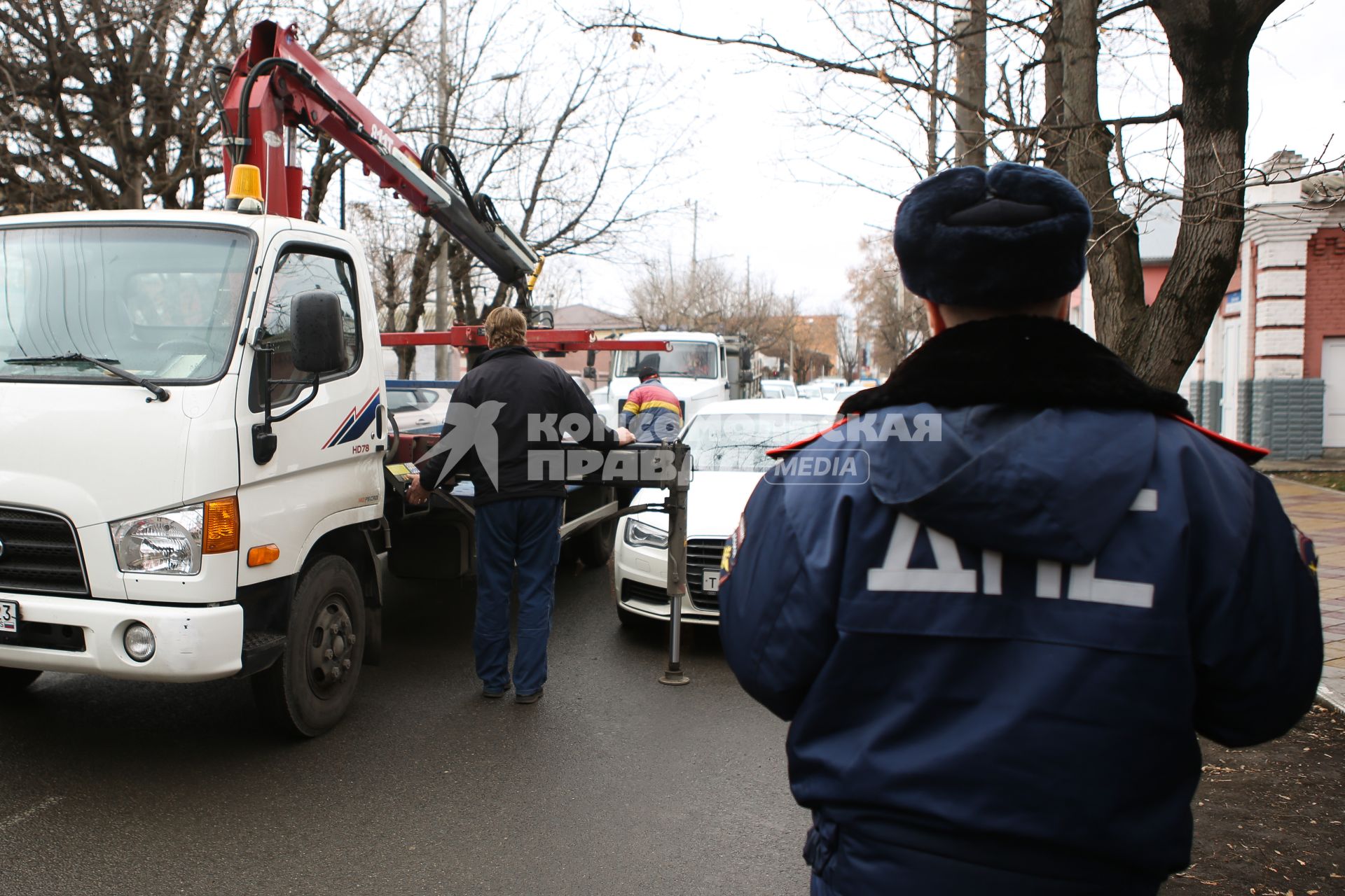 Инспектор ДПС составляет протокол и эвакуирует машину за неправильную парковку.