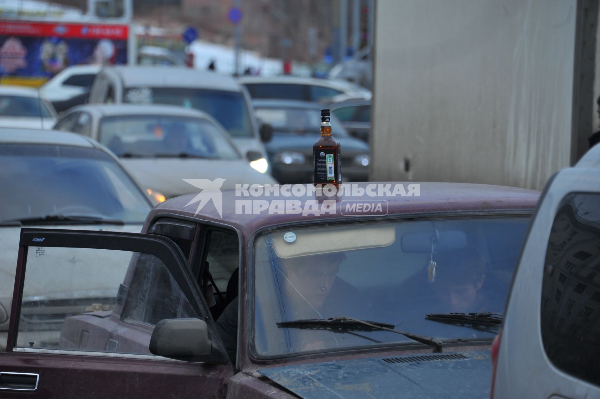 Парковка автомобилей. На снимке: бутылка с алкоголем на крыше автомобиля.