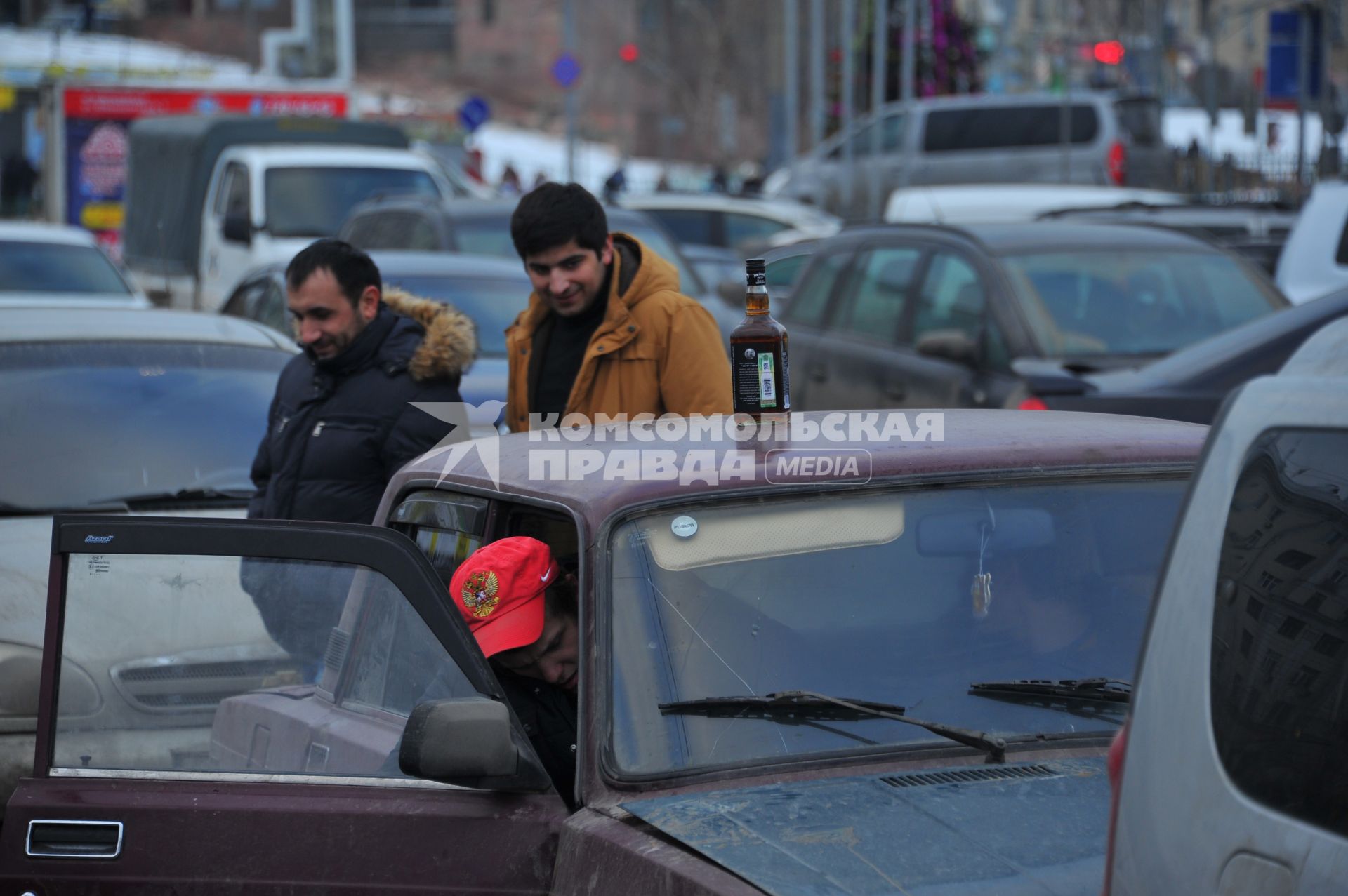 Парковка автомобилей. На снимке: бутылка с алкоголем на крыше автомобиля.