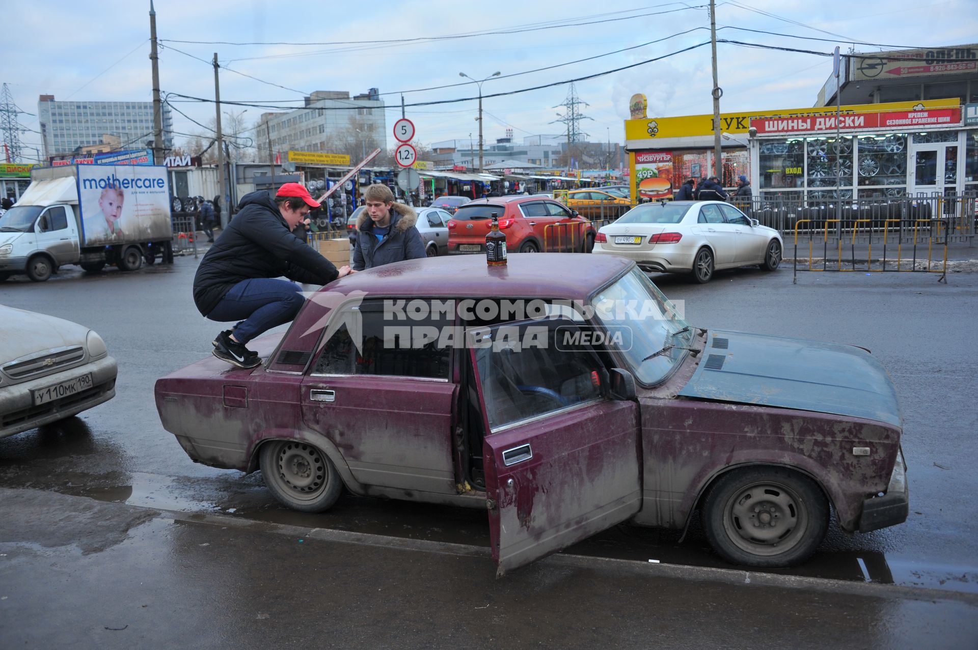 Мужчина сидит на багажнике автомобиля.