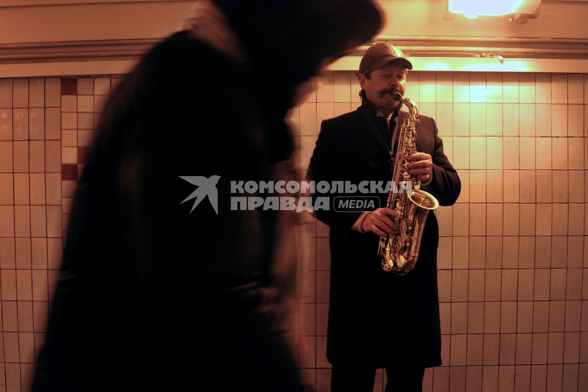 Саксофонист играет в подземном переходе.