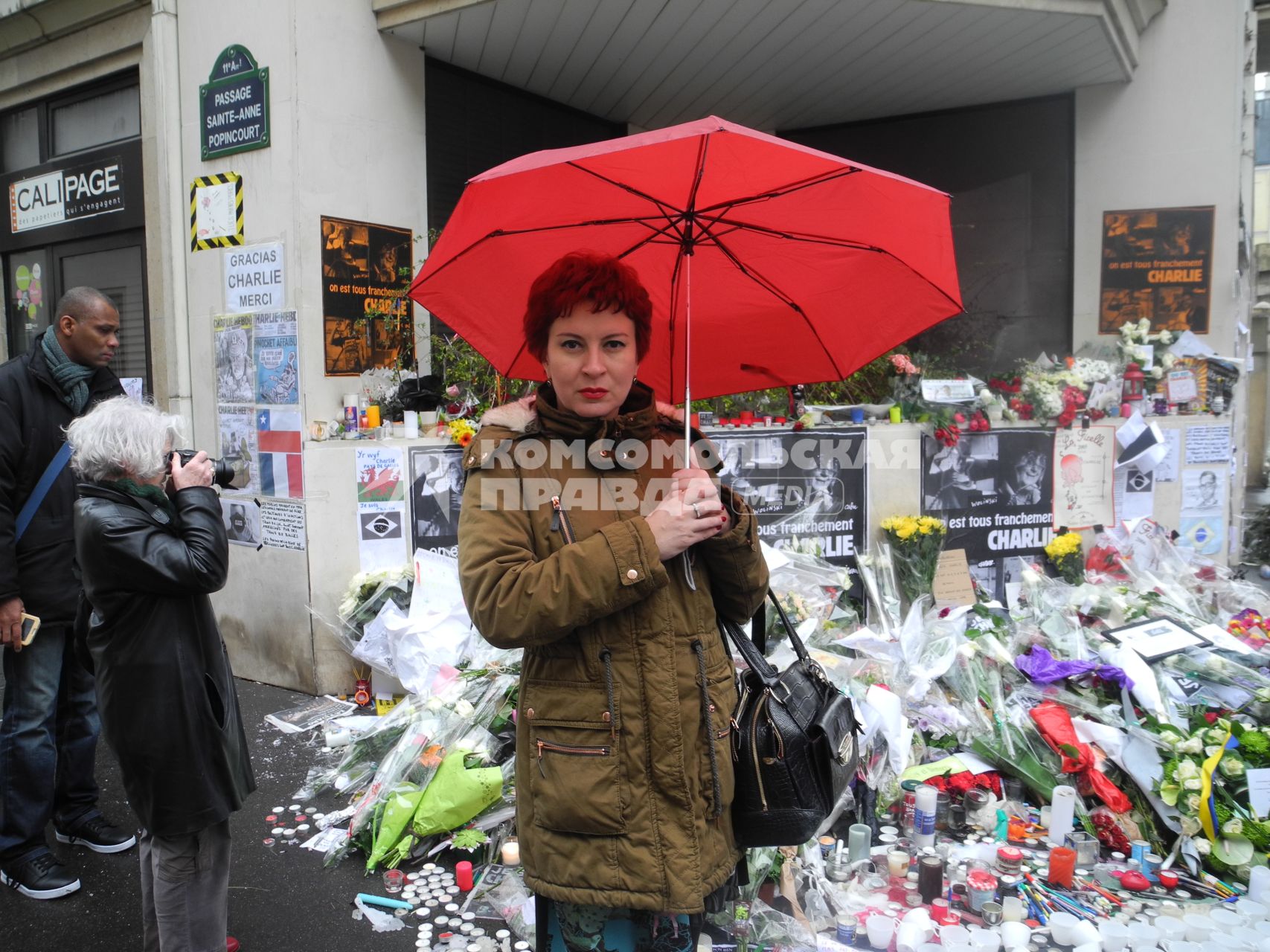 Париж. Цветы и свечи у здания редакции сатирического еженедельника Charlie Hebdo в память о жертвах нападения террористов 7 января. В результате стрельбы погибли 12 человек. На снимке: специальный корреспондент КП Дарья Асламова.