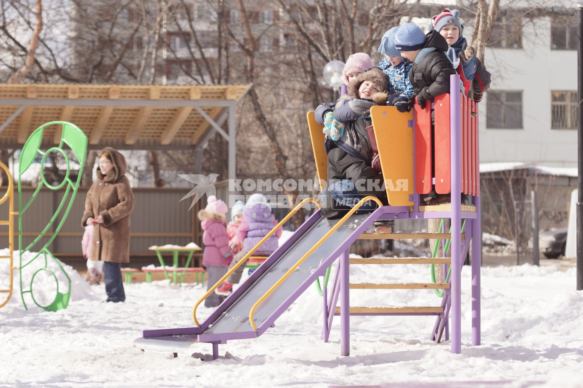 Дети катаются с горки на детской площадке в садике