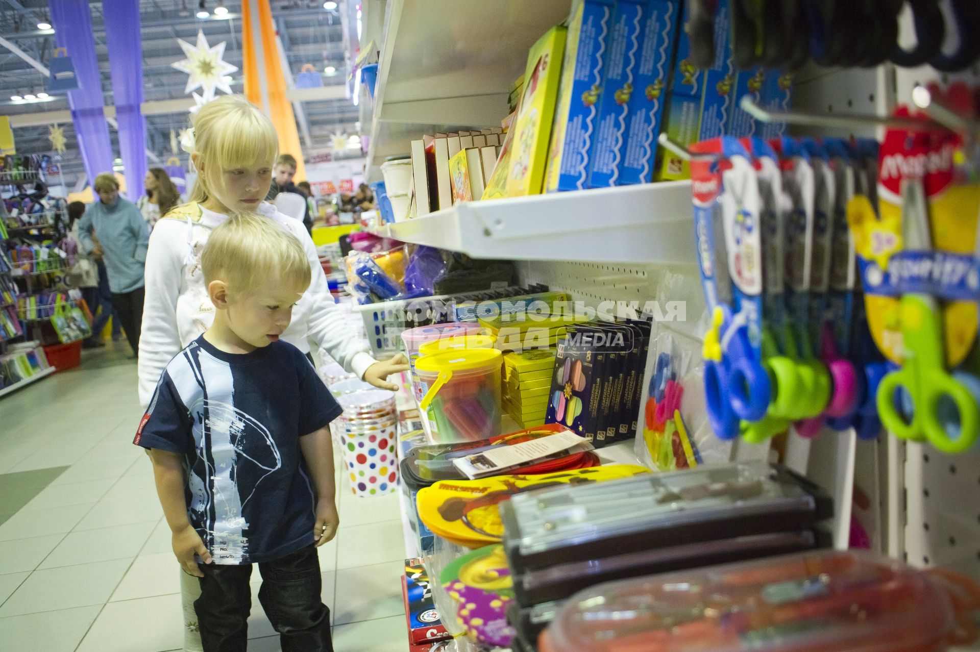 девочка и мальчик выбирают мелки в магазине. Школьный базар