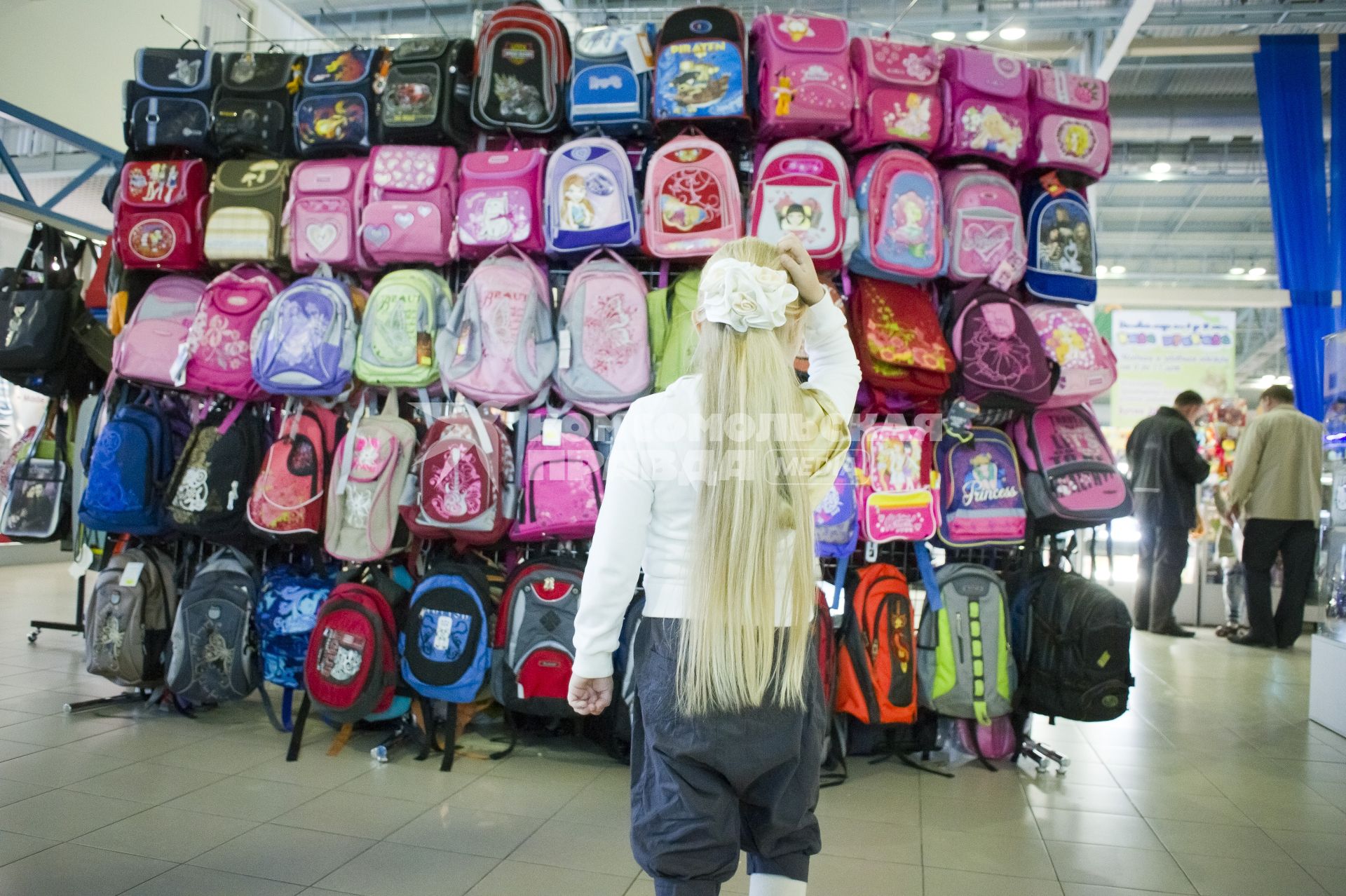 девочка выбирает школьный портфель в магазине. Школьный базар