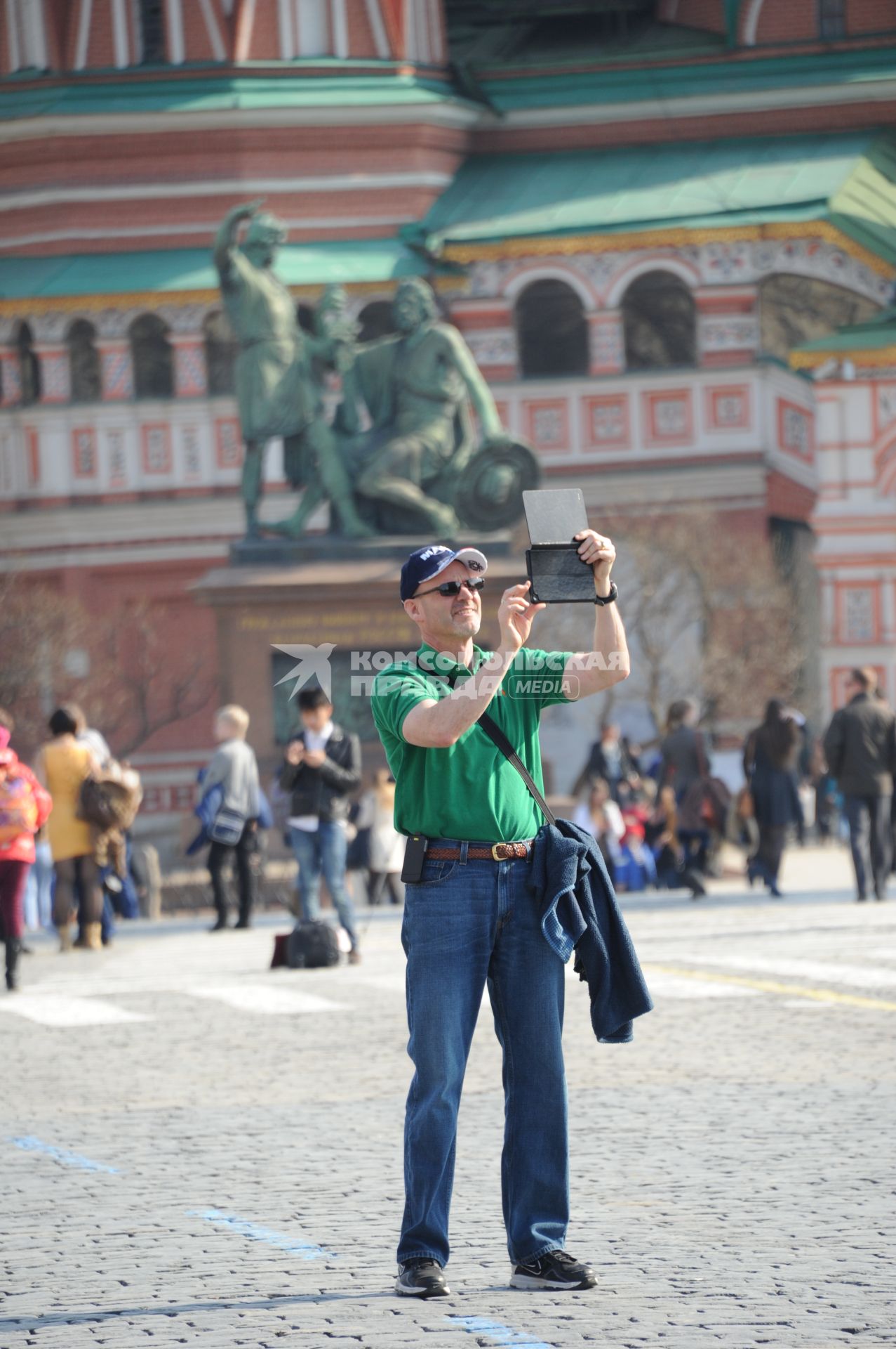 Мужчина фотографирует с помощью планшетника Красную площадь.