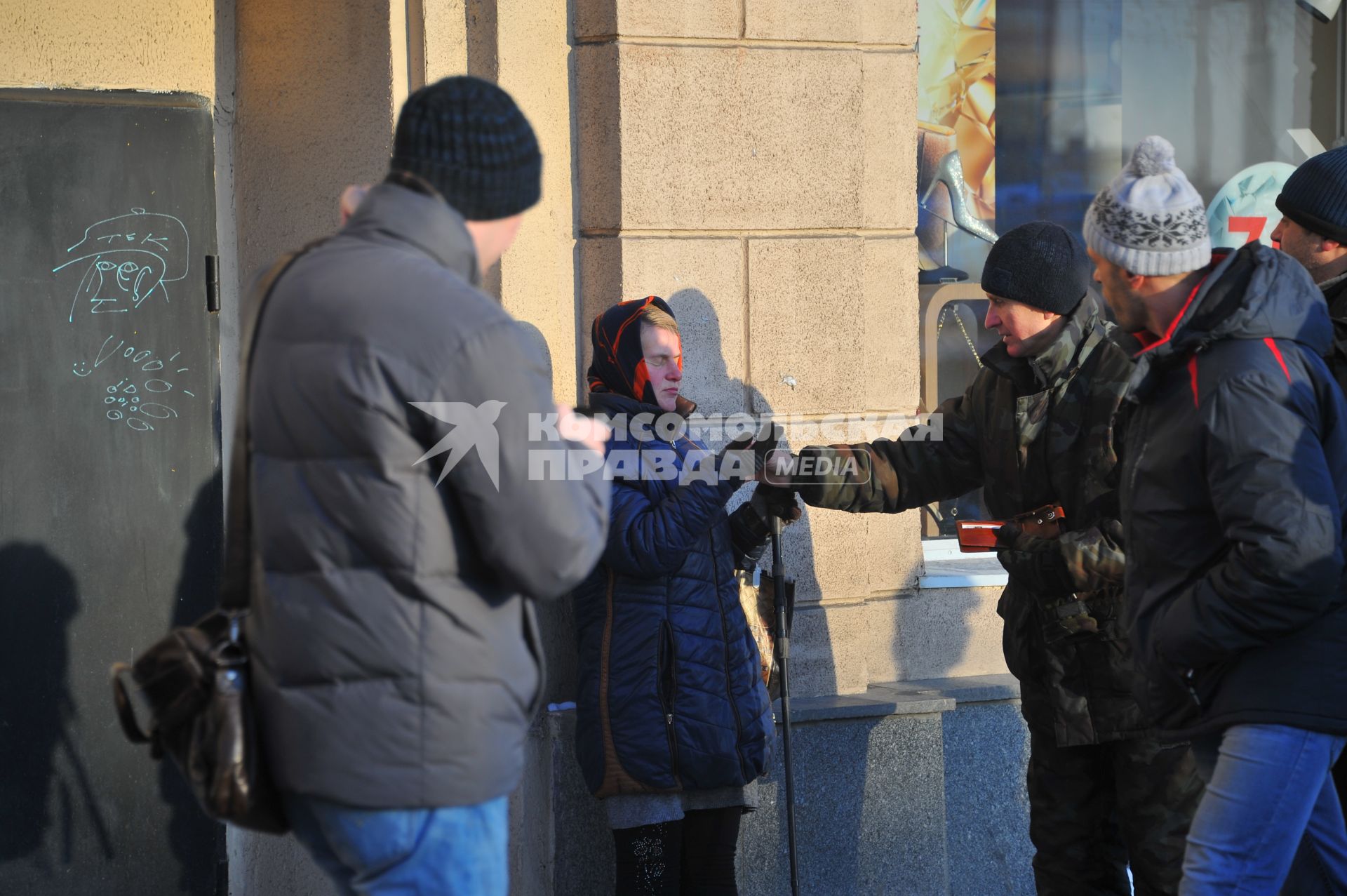 Девушка с зашитыми глазами просит подаяния.