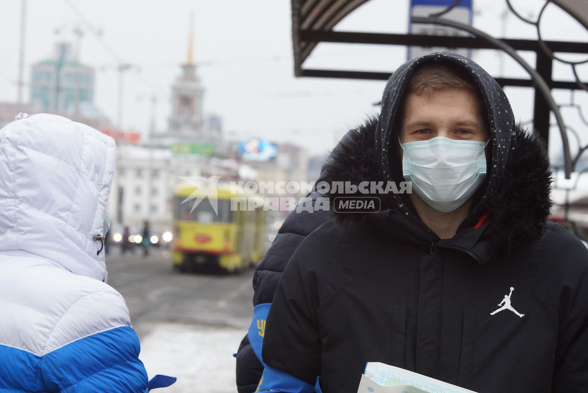 парень в медицинской маске на трамвайной остановке. Акция \"МАСКАрад\" в Екатеринбурге, в ходе которой горожанам раздавали маски, для снижения заболеваемости ОРВИ.