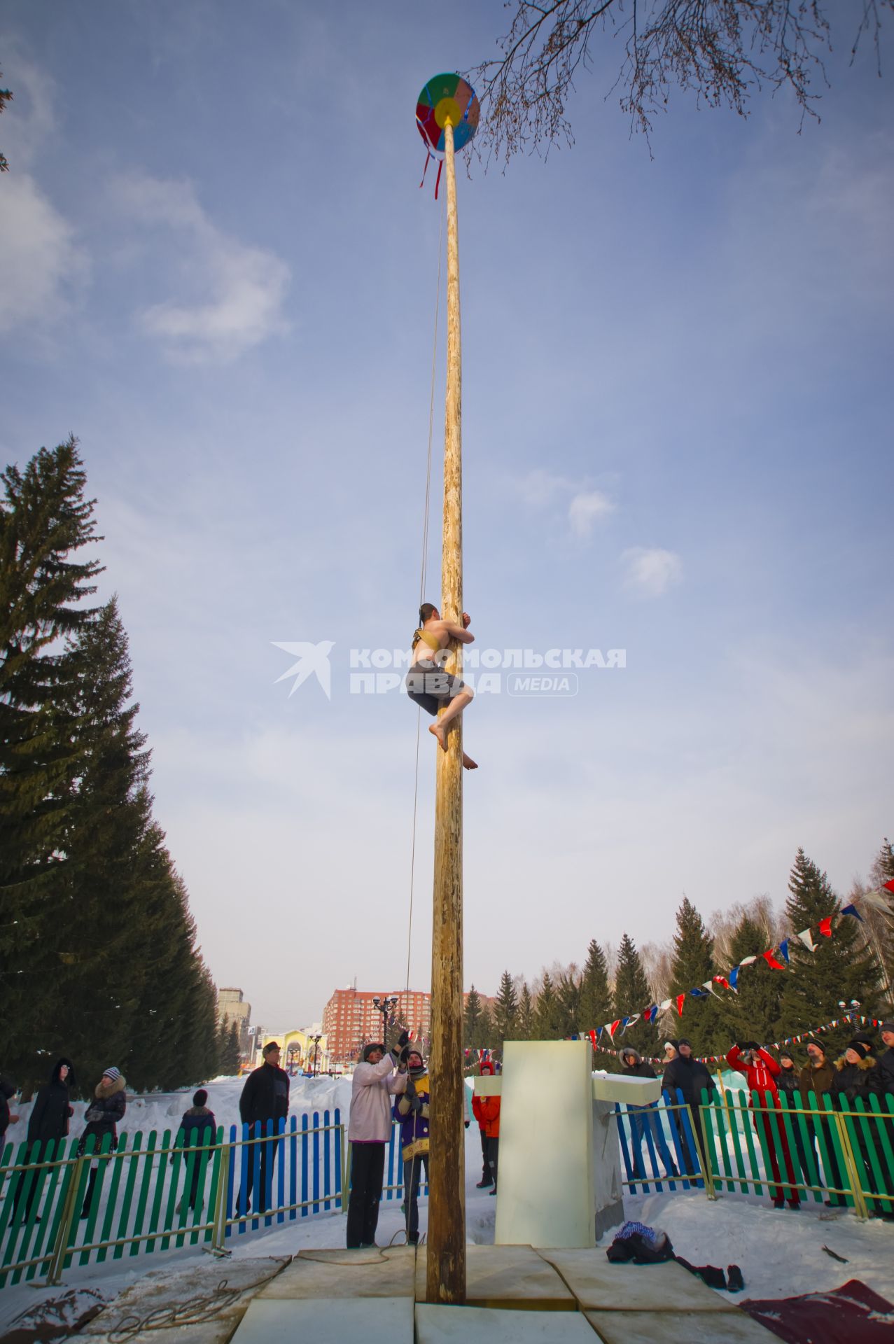 Мужчина лезет на деревянный столб, во время празднования масленицы в Екатеринбурге