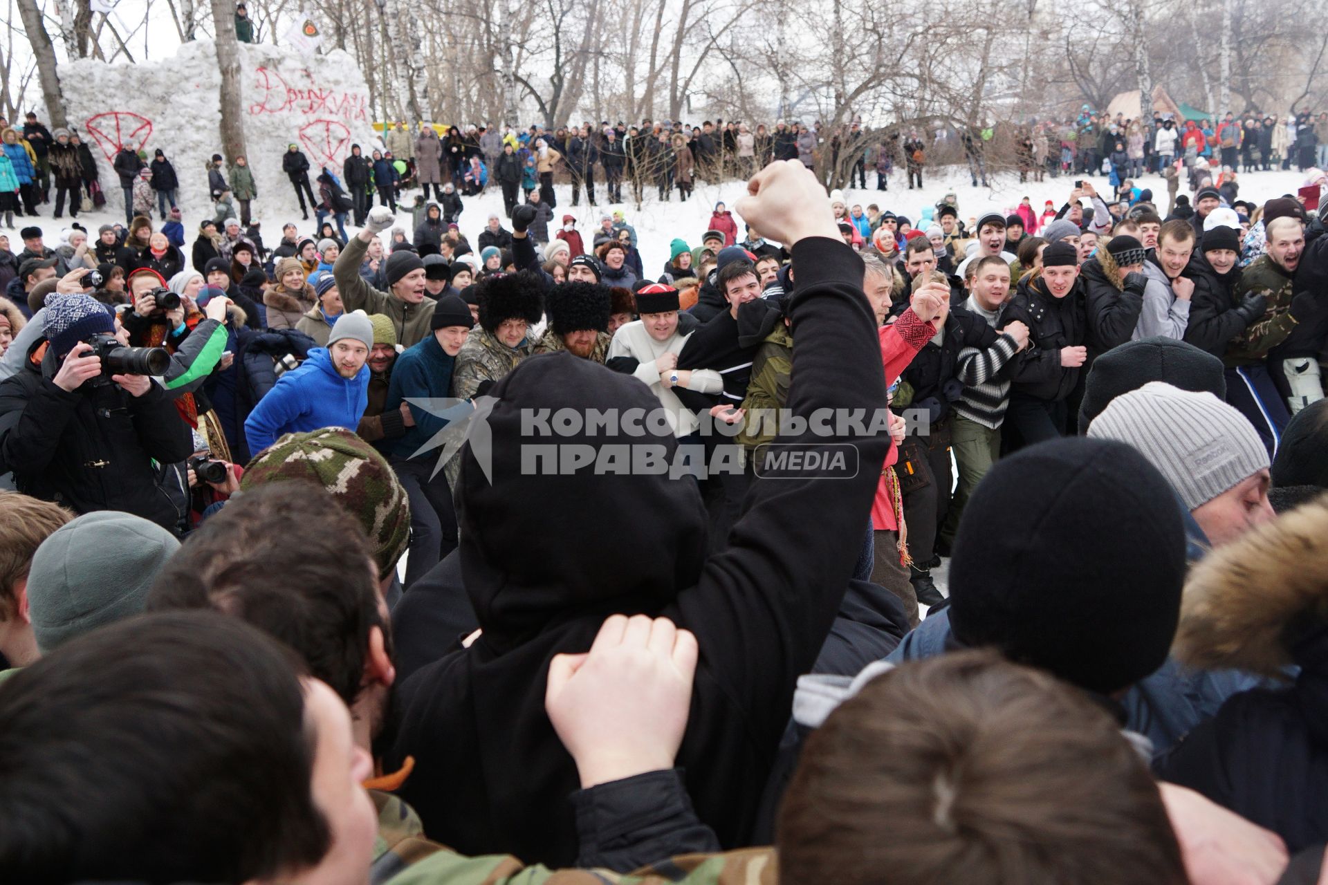 Молодые парни и мужчины участвуют в народной забаве \"Стенка на стенку\". Празднование Масленицы в Харитоновском парке, в Екатеринбурге