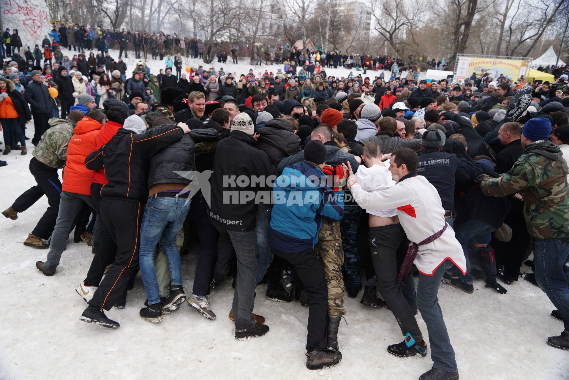 Молодые парни и мужчины участвуют в народной забаве \"Стенка на стенку\". Празднование Масленицы в Харитоновском парке, в Екатеринбурге