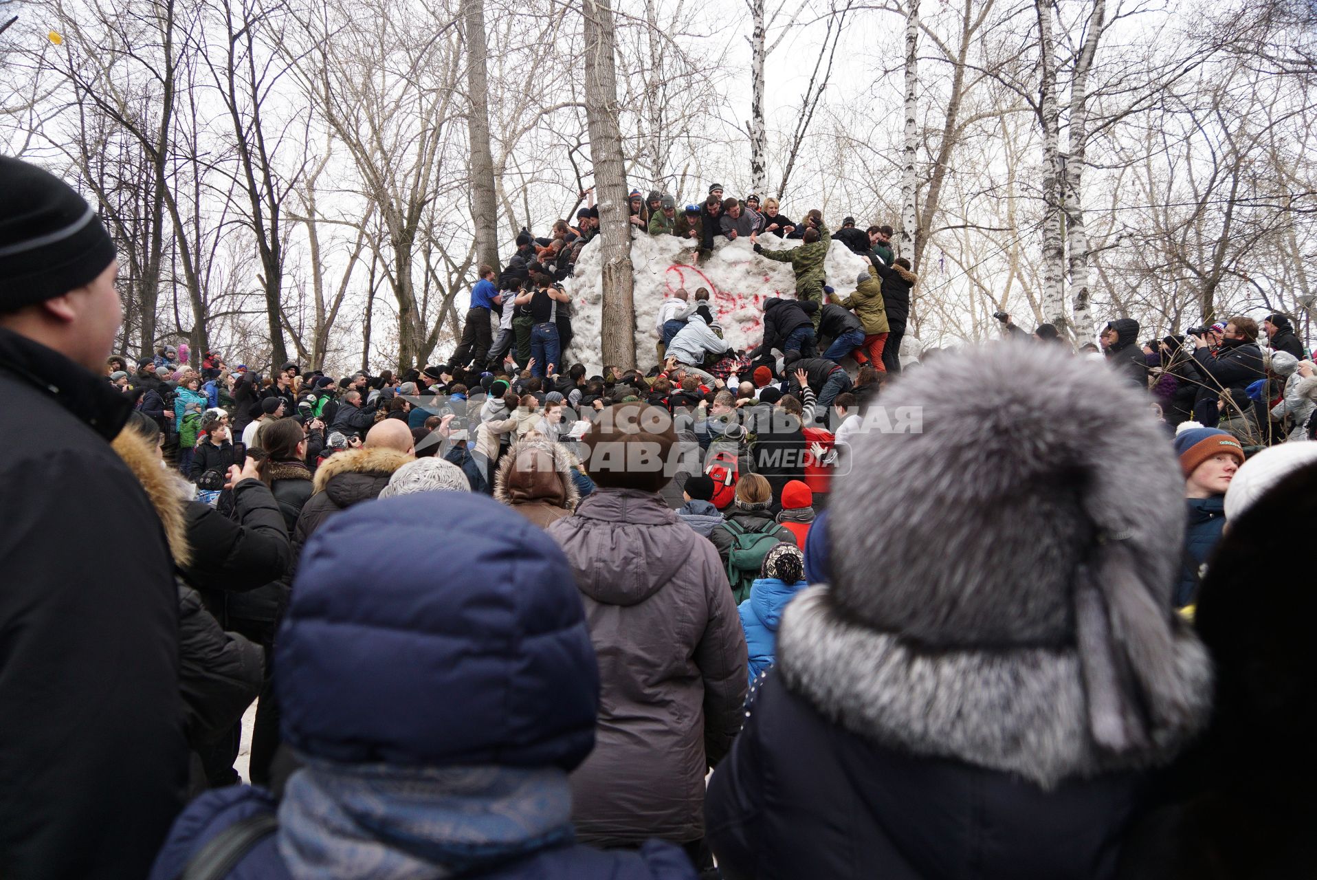 Молодые парни штурмом берут снежную стену. Празднование Масленицы в Харитоновском парке, в Екатеринбурге